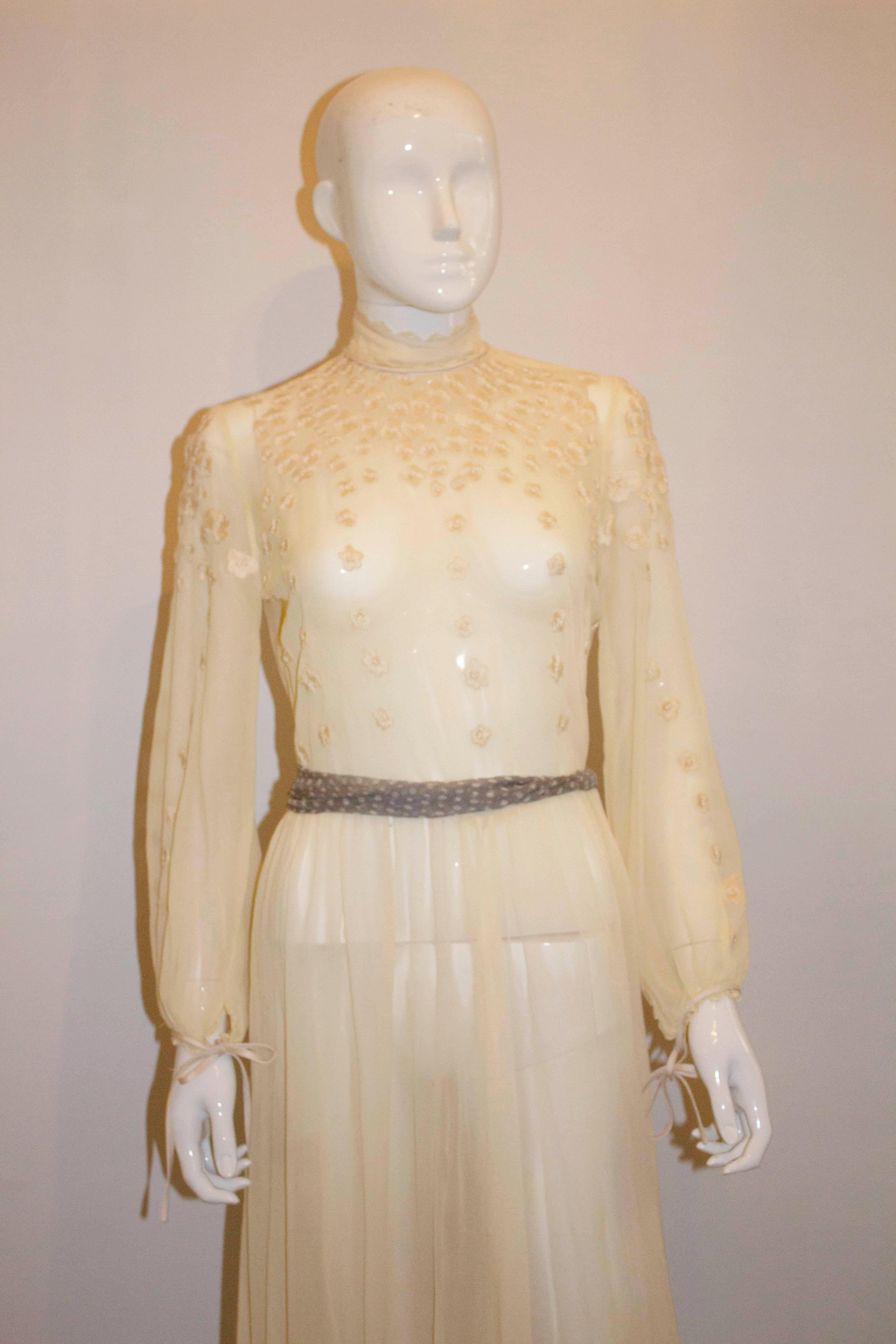 A stunning vintage couture gown in a pretty ivory colour with wonderful embroidery detail. The dress has a stand  up collar , with a ribbon tie  at the neck ( could be removed), gathering at the waist and ties at the wrist.

Measurements: Bust up to