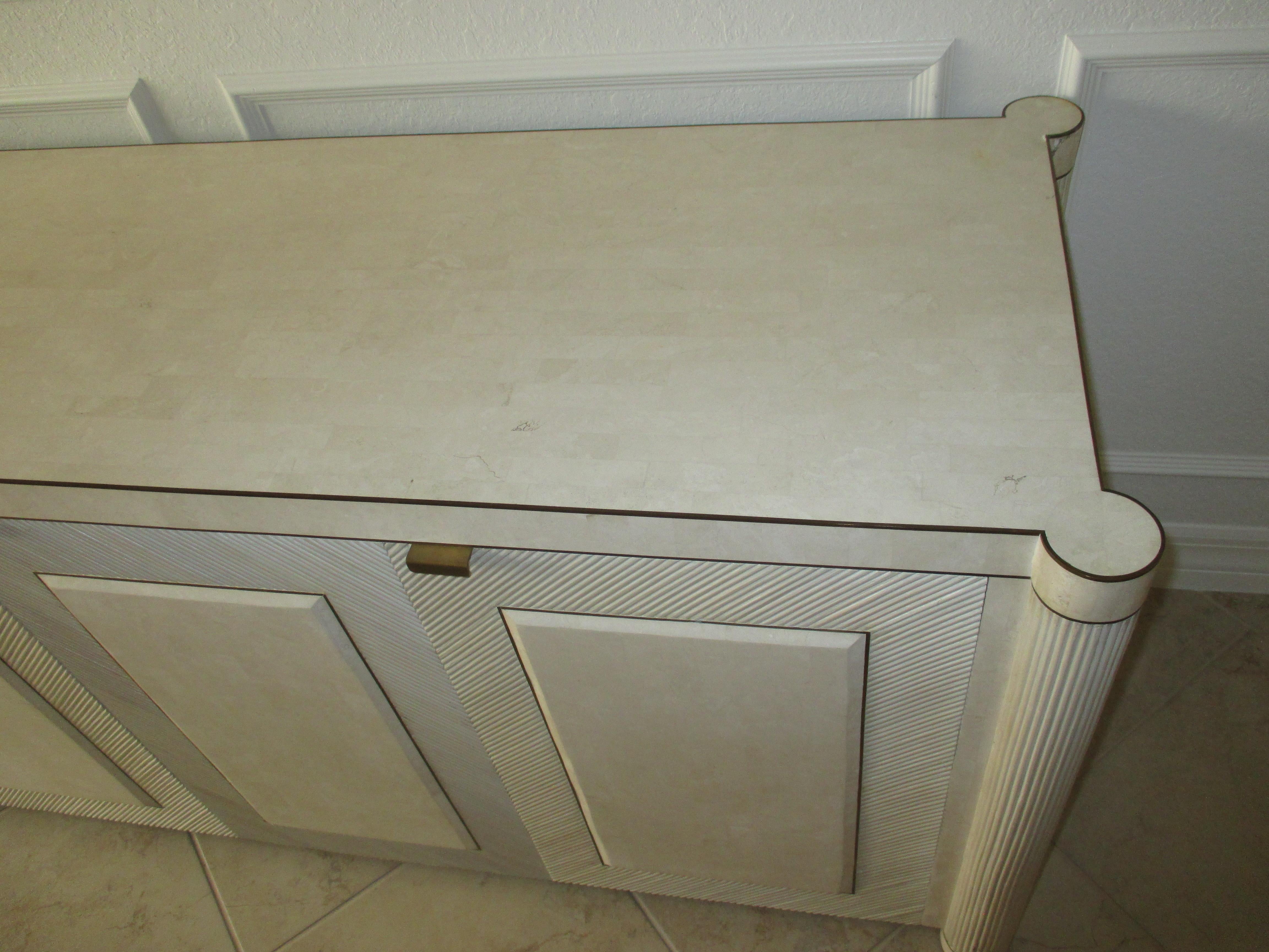 Split bamboo-over-wood sideboard with an ivory finish, tiled top, and brass accents. Each door has a tiled panel inset: the middle two doors open to a top drawer and middle shelf and the side doors open to cabinets, with one containing a middle