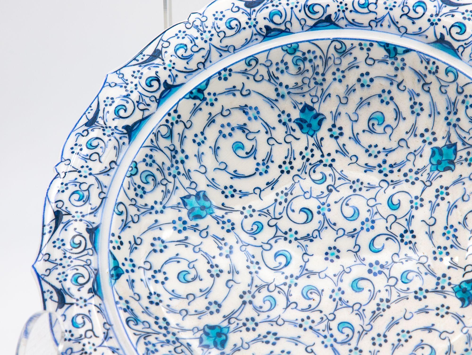 A stunning Iznik plate in a piecrust shape. This beautiful example of early 20th-century Iznik pottery features the iconic cobalt and turquoise colors on a white background that this Turkish style of pottery is known for. There is a repeating flower