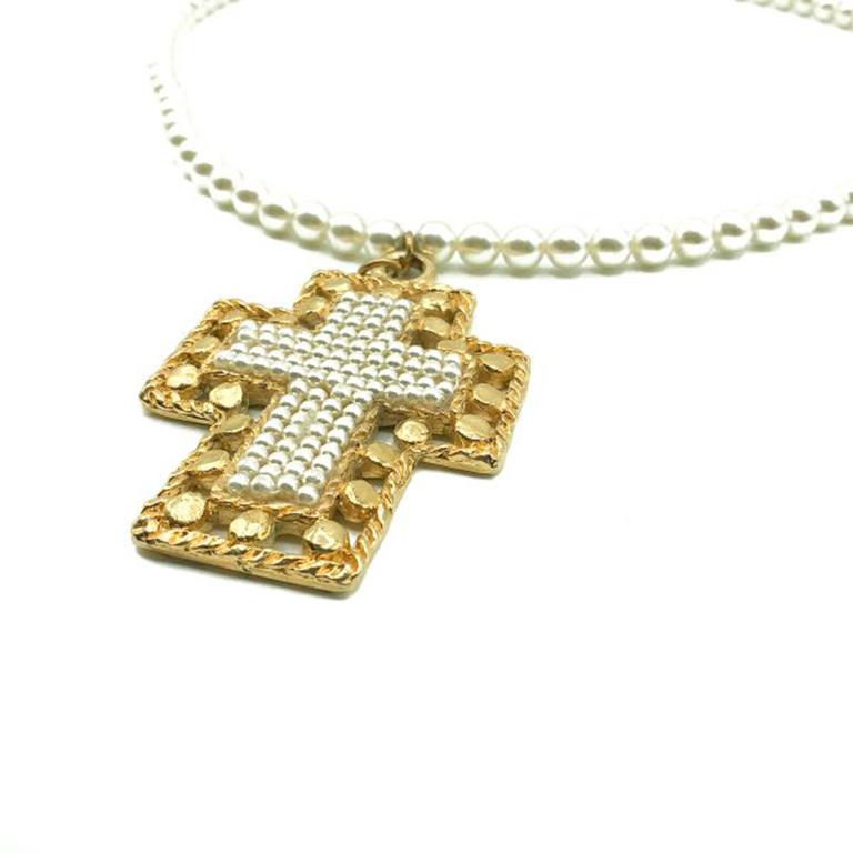 A Vintage Jacky de G Paris Cross Necklace. Crafted in Paris from gold plated metal and glass simulated pearls. Featuring a long pearl rope necklace with an ornate gold and pearl cross pendant. In very good vintage condition, signed, 65cms. A truly