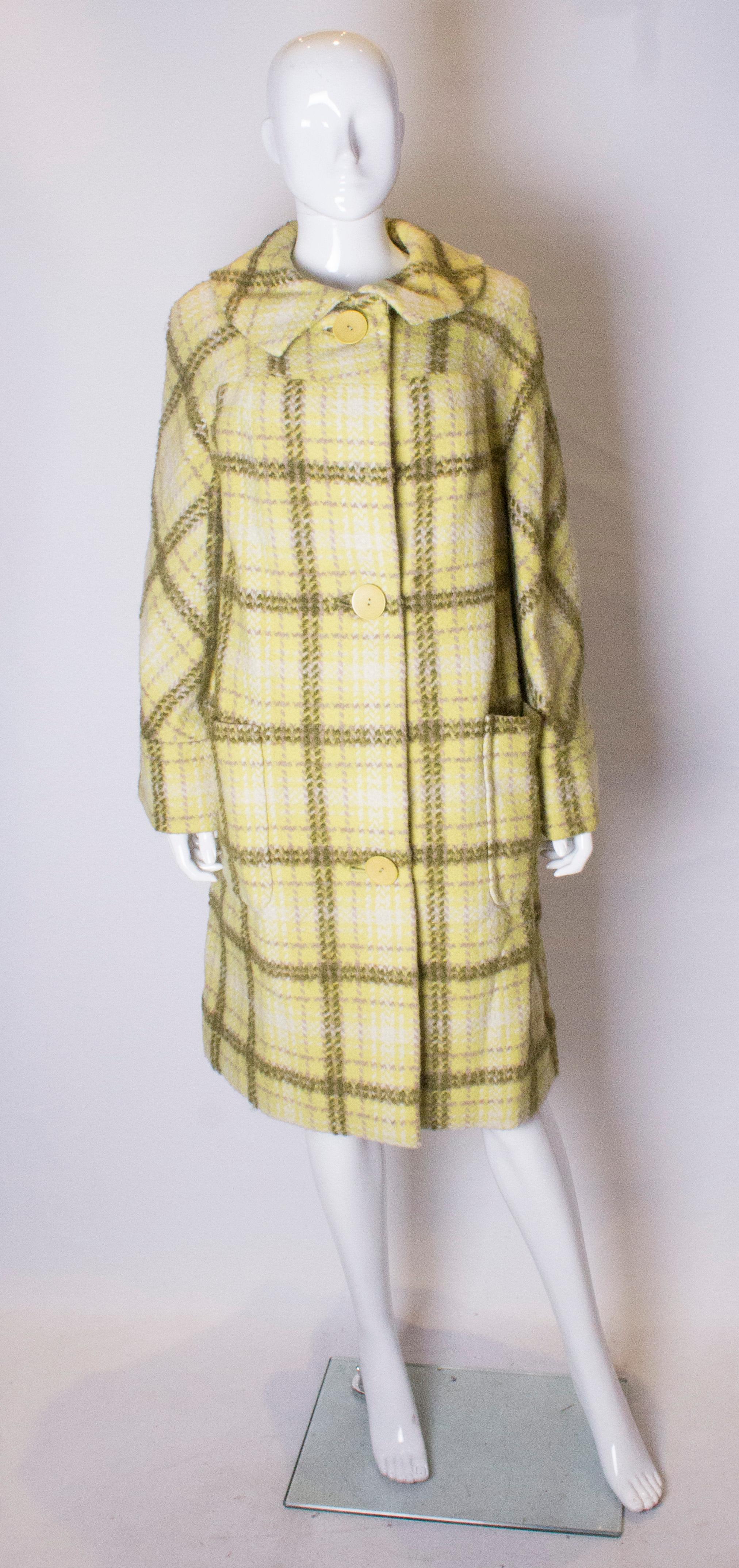 A chic coat by Jacqmar. The coat has a yelllow background with olive, lilac and white stripes. It has a round collar, three button opening and two large patch pockets. It is fully lined and there is an additional fabric swatch. 
