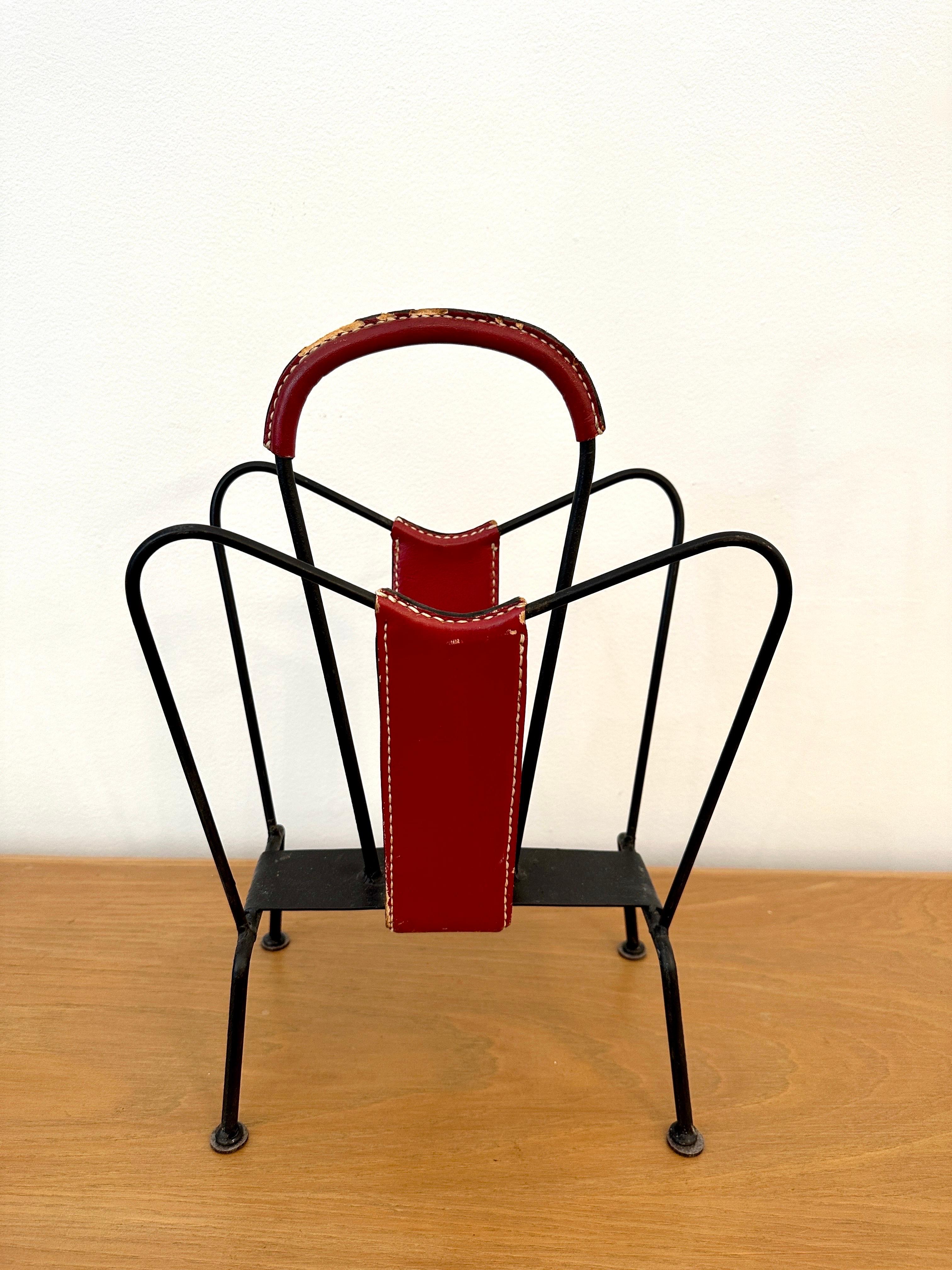 Magazine stand designed by Jacques Adnet and manufactured in his own atelier, France, 1950. The magazine stand has a solid frame and is accented by handstitched red leather. The stand has a nice patina from age and usage, and is fully in original