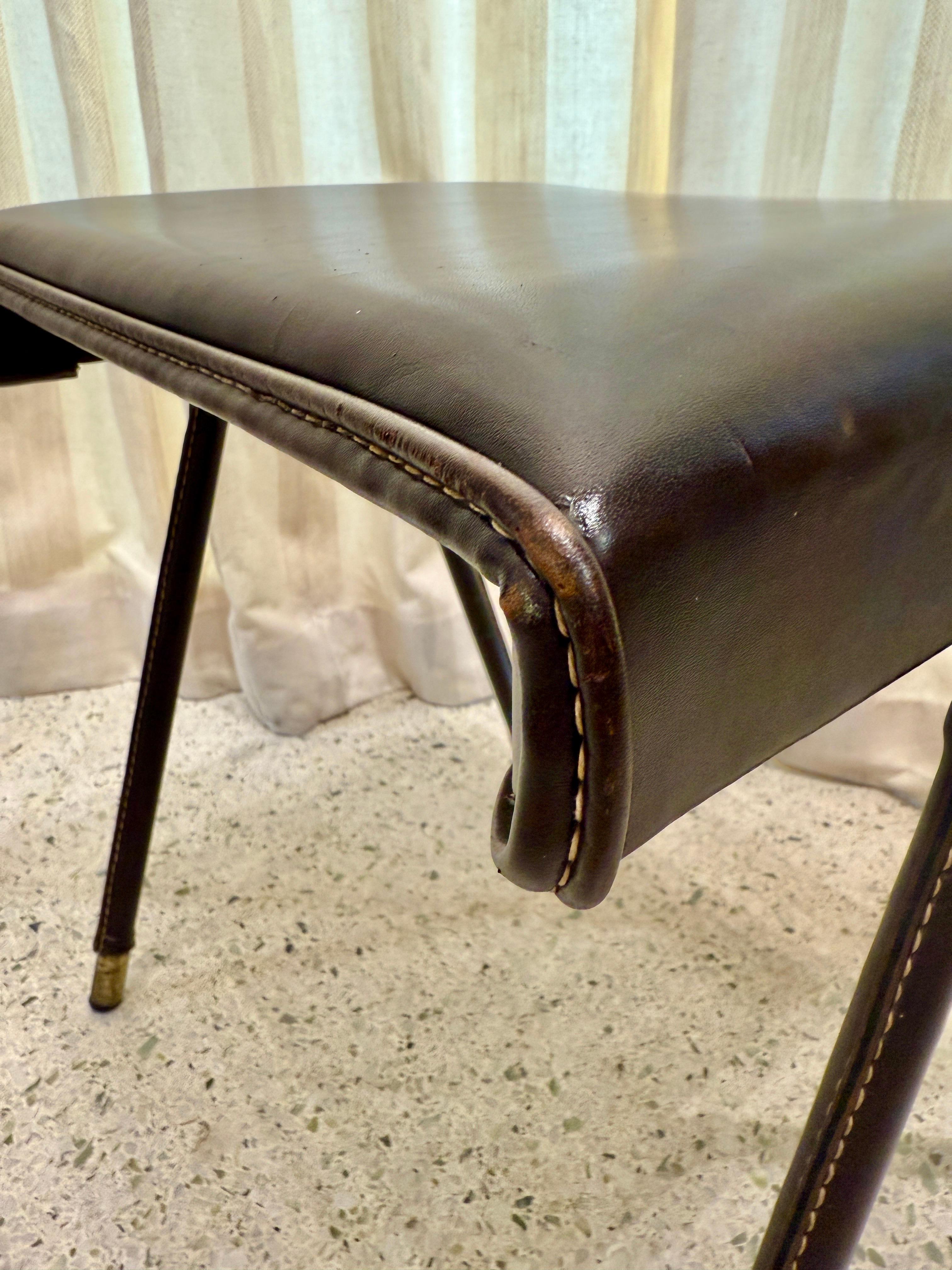 This is an original Jacques Adnet stool/ bench in dark brown stitched leather and brass accent feet.  Beautiful from all angles and perfect for added seating.  NOTE:  we have a desk and valet stand which came as a set ALL in the same chocolate brown