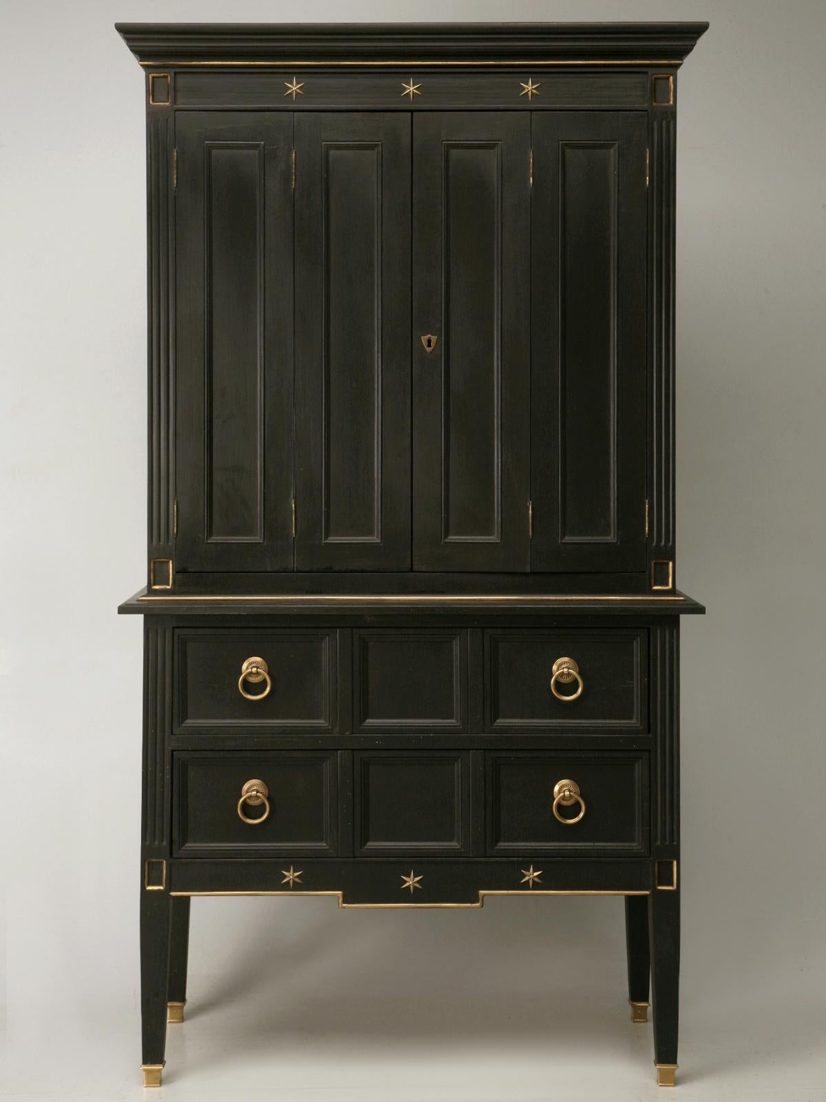 Stunning French 1940's Jacques Adnet style cupboard with double bi-fold doors over a lower base section with two convenient and very useful full width drawers. The finish is black paint with contrasting gold highlights, the bronze stars add extra
