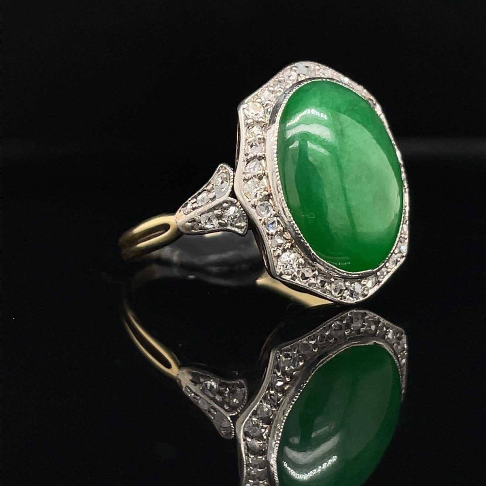 A vintage jade and diamond engagement ring in 18 karat yellow gold, circa 1940.

This ring features a central oval cabochon of 'imperial green coloured' jadeite, estimated as 4.40 carats bezel set in platinum within a delicate and light cluster of
