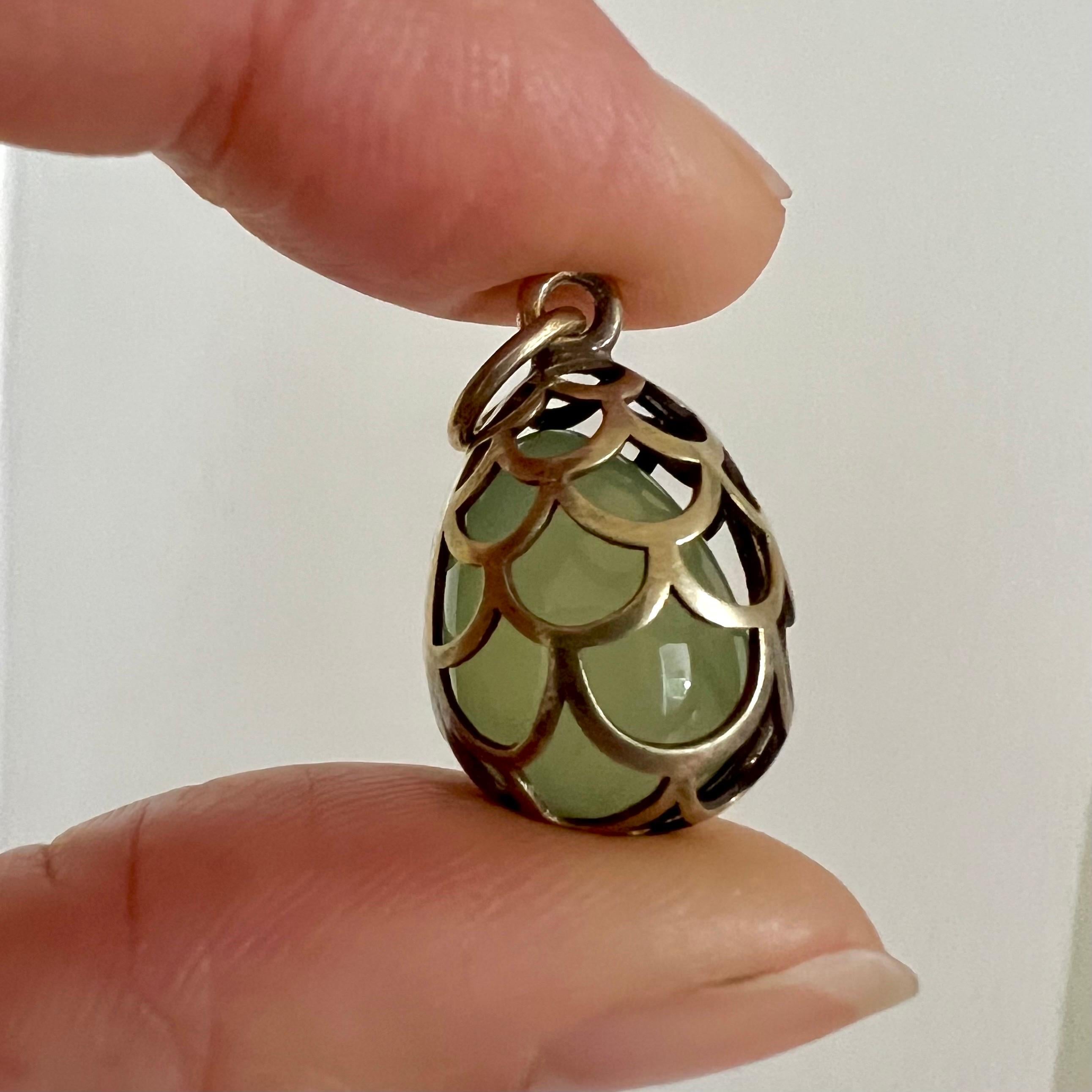 This exceptional Russian jade pendant embodies a harmonious blend of elegance and craftsmanship. At its core lies a mesmerizing jade egg, nestled within an intricately crafted gilt silver openwork cage, exuding an air of sophistication and
