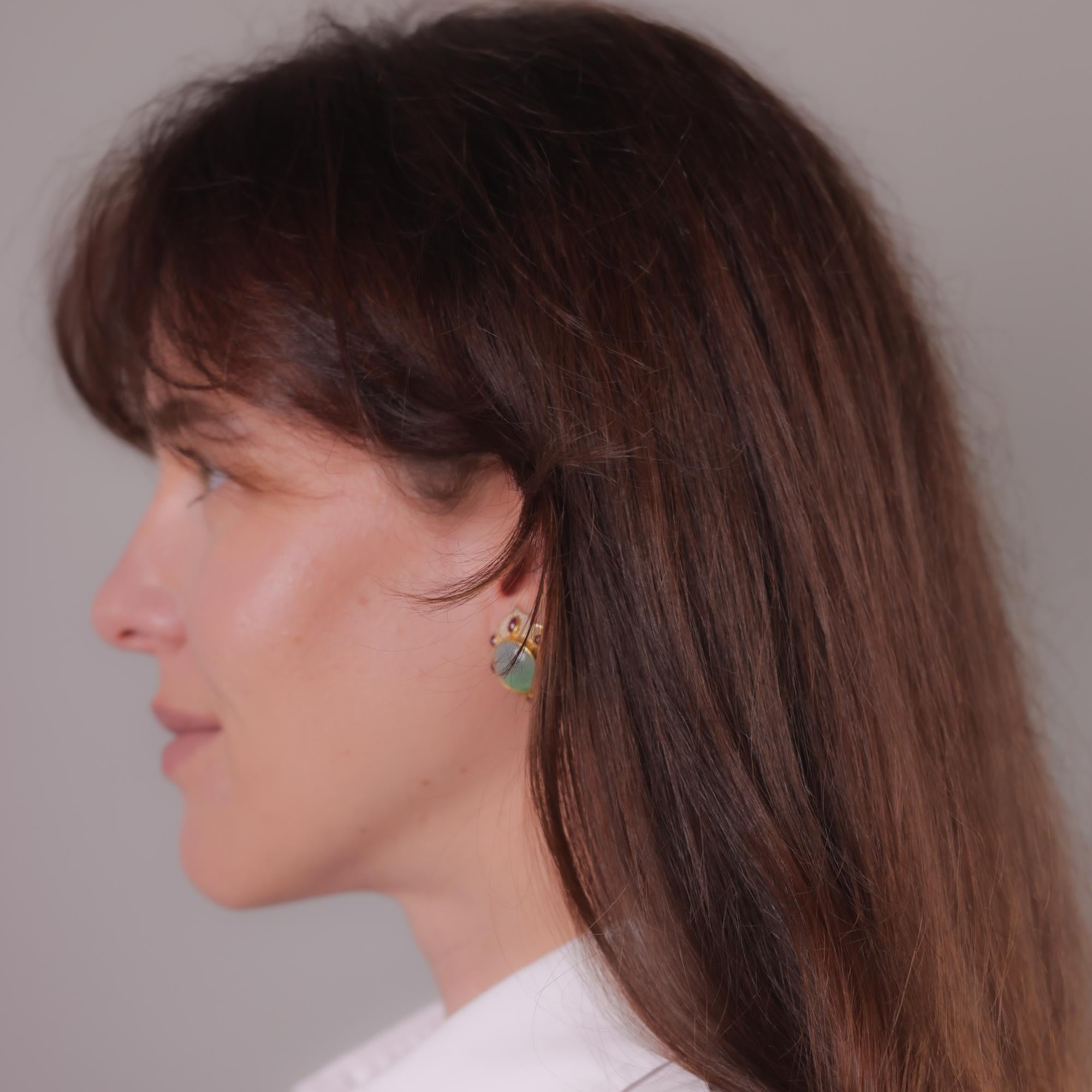 Elegant vintage 18k yellow gold earrings featuring lush cabochon jade, vibrant rubies, and delicate seed pearls, radiating timeless charm.

Center stone: 2 cabochon cut jade
Weight: Approximately 13mm across each
Accent stone: 12 cabochon cut