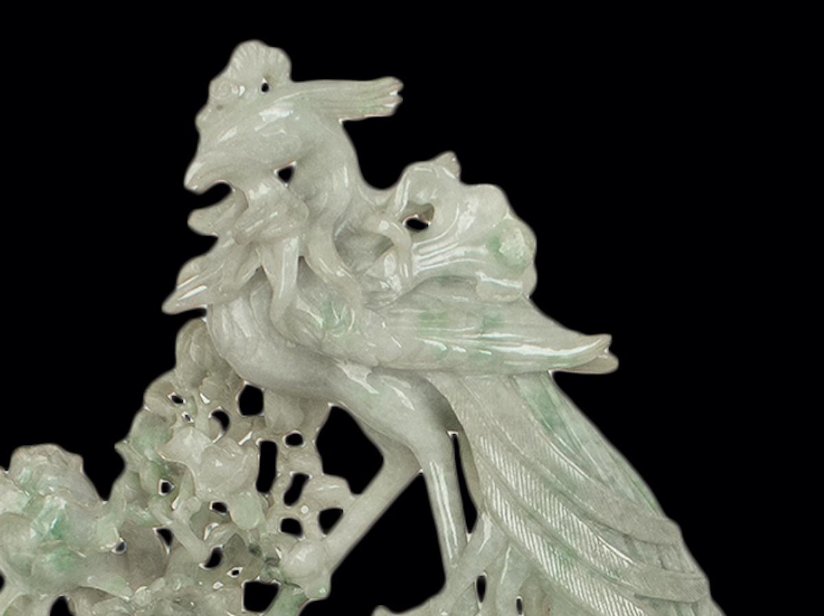 This is a superb jadeite carving, realized in China in the 20th century.

Pale green jadeite with some darker green inclusions, carved with two vases, floral branches and a phoenix on the top.

Includes base: totally dimensions H 37