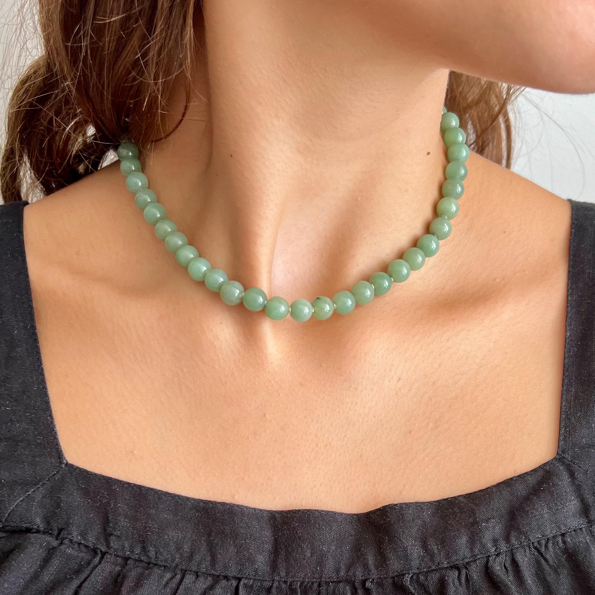 A lovely vintage green jade single-strand beaded necklace. The necklace consists of round-shaped jade stones and the beads have a very nice green color. To keep some space between the beads, green thread is knotted in between. The 14 karat gold