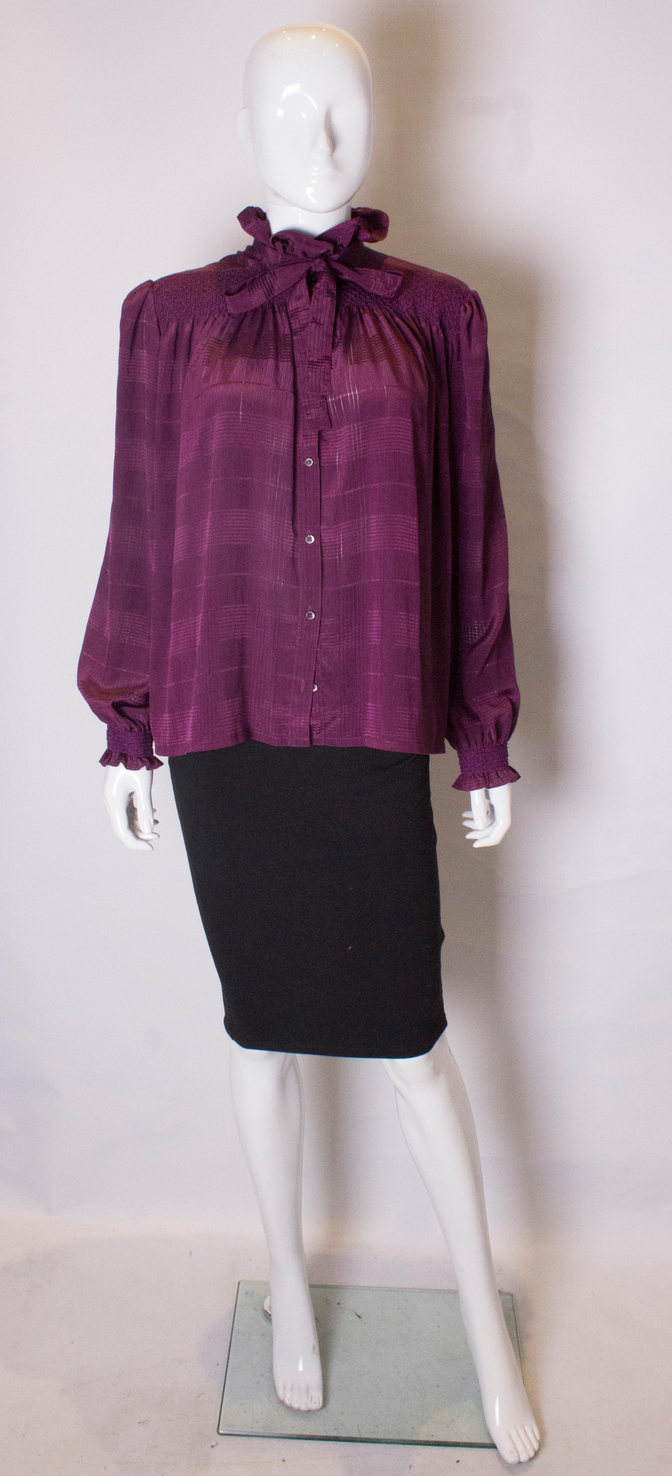 A chic and easy to wear vintage blouse by Jeager. The blouse has interesting smocking detail on the front and cuffs, and has a button through front and self fabric neck tie.