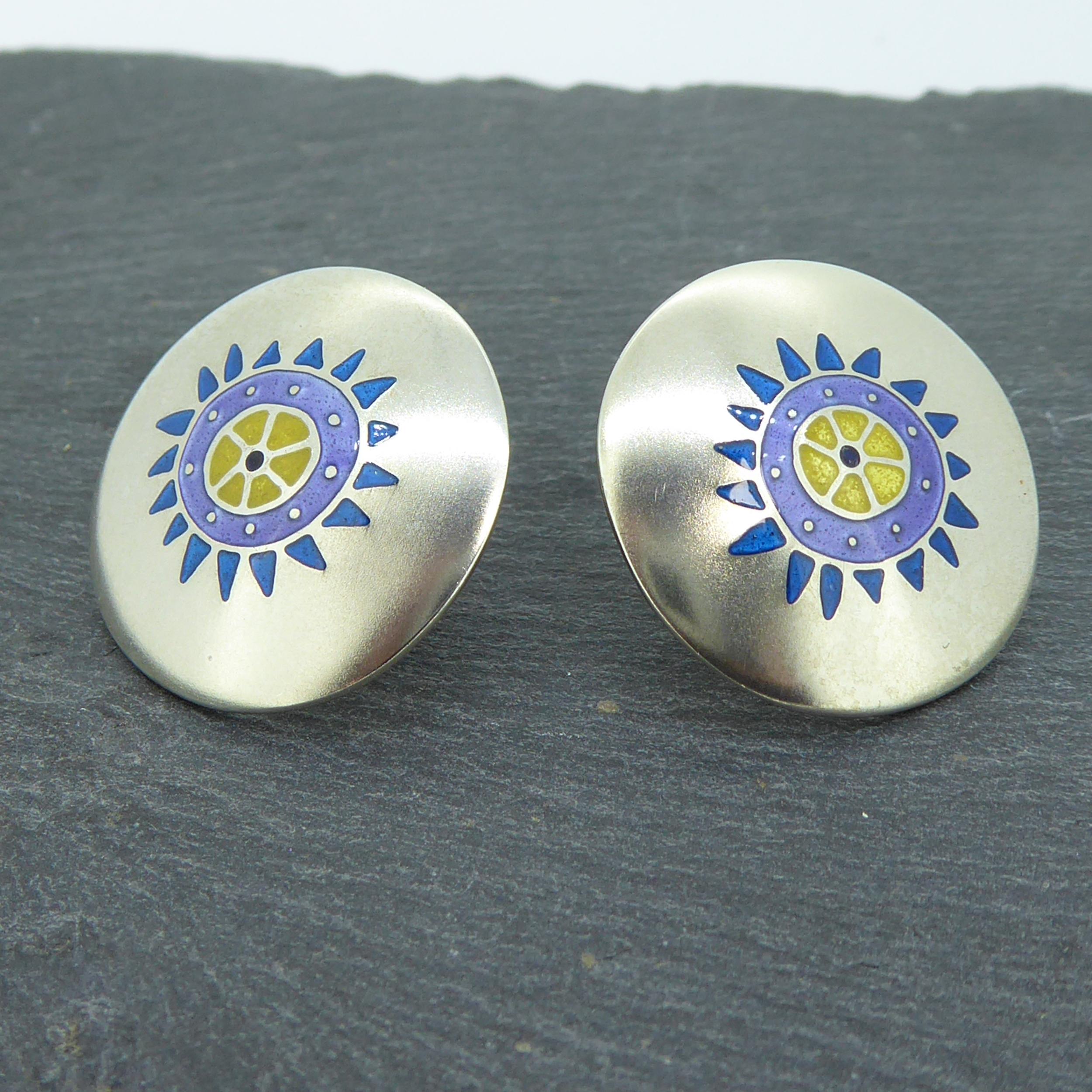 A pair of recent vintage Jane Moore earrings hallmarked in 1996.  Created in silver with a stylized floral pattern in subdued enamelled colours of teal,, lilac and lemon, the earrings are slightly domed to the front with the back 