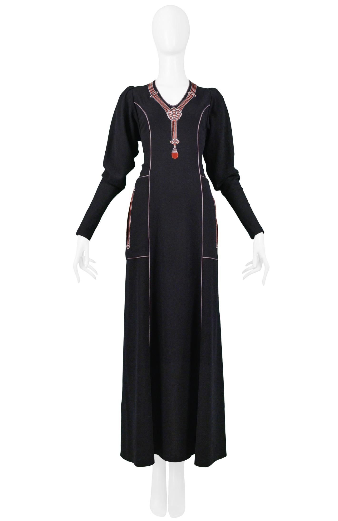 Vintage Janice Wainwright Art Deco-inspired black wool long sleeve maxi dress featuring an embroidered pendant necklace at the neckline, front slit pockets, and cord detailing at the seams. Center back zipper closure. Circa 1970s.

Good Vintage