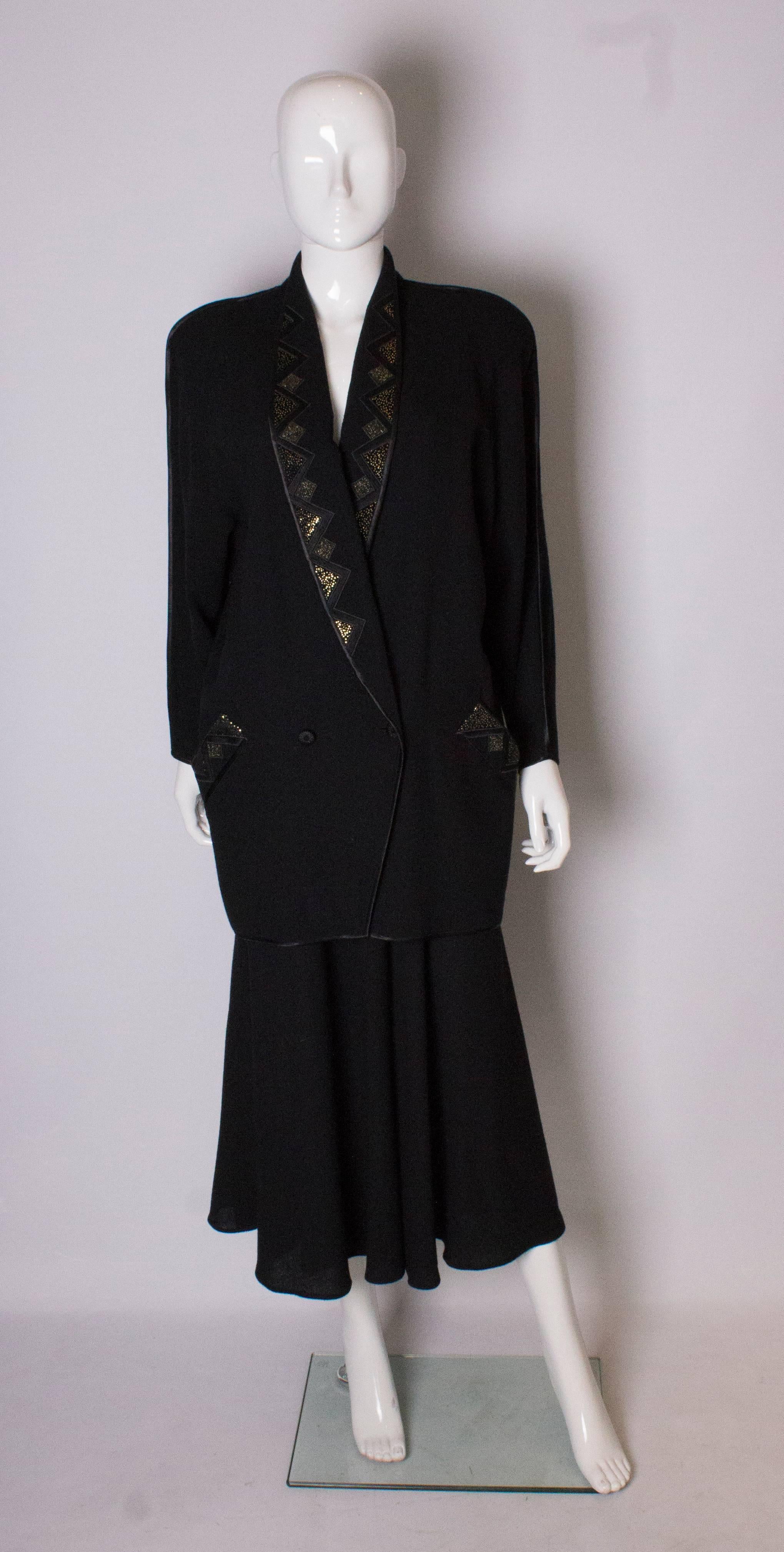 A chic vintage skirt suit by Janice Wainwright. The jacket has a deep v neckline, with shawl collar and with detail on the lapels.  It has a two button fastening, two sloping pockets and ribbon trim on the edges. It is labelled size 10. 
The skirt