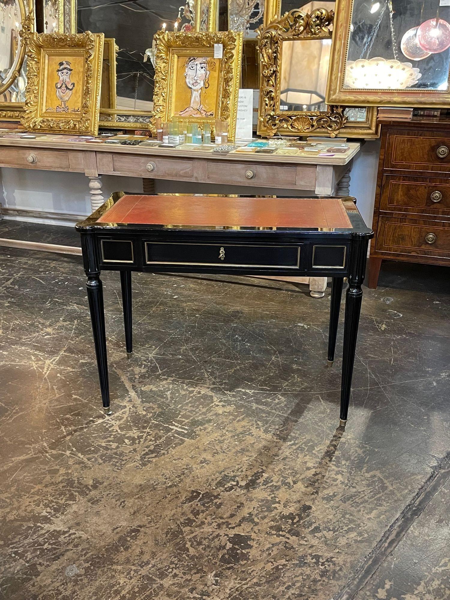 Handsome vintage Jansen style black lacquered writing desk. Beautiful clean lines with gold accents and a leather top. Adds a real touch of elegance!.