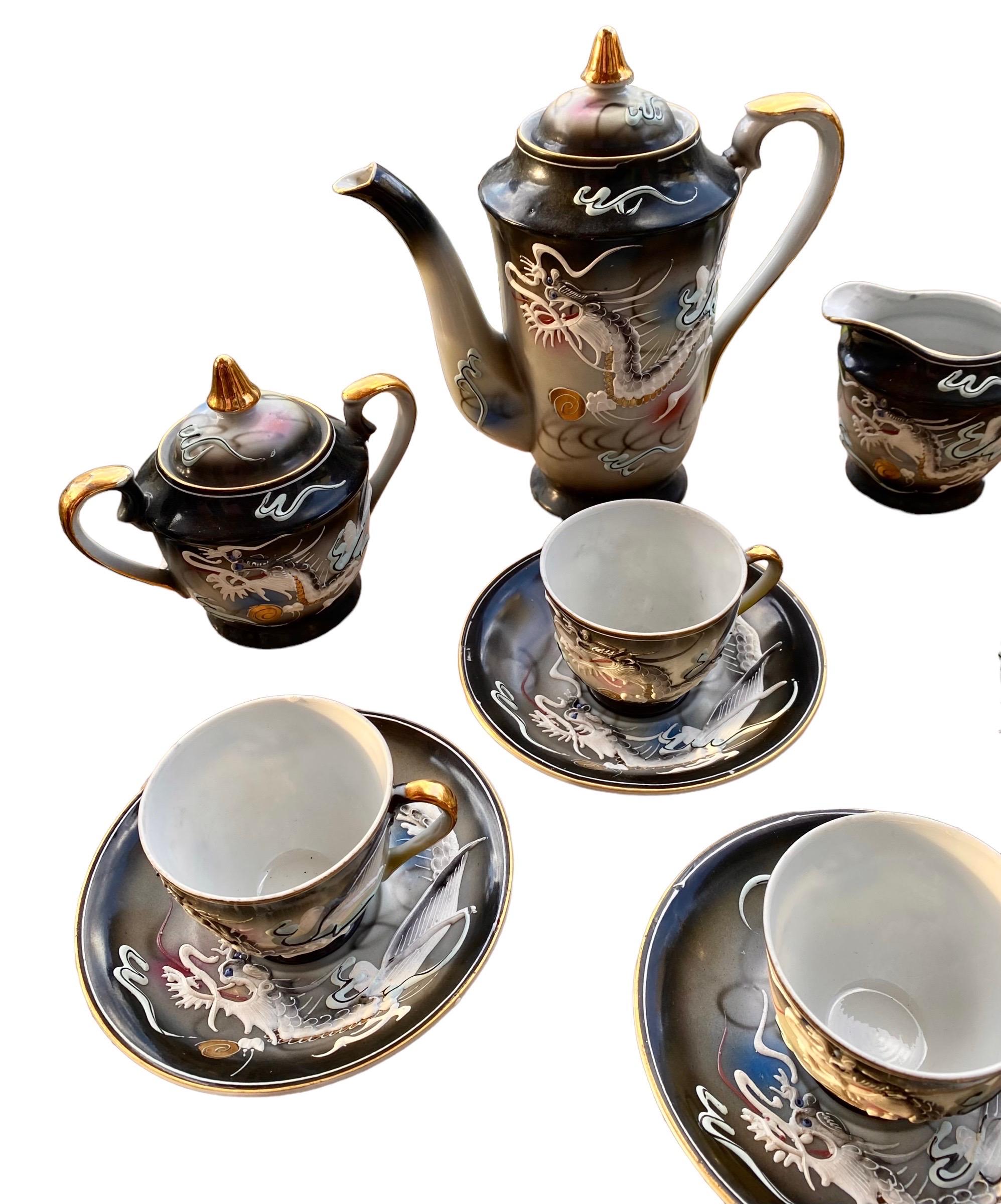A lovely, artisanal, handcrafted porcelain Japan dragon ware tea set consisting of six demitasse cups and saucers, sugar bowl with lid creamer and tea pot with lid. The delicate, lovely dragon designs are raised and extremely textural, a delight to