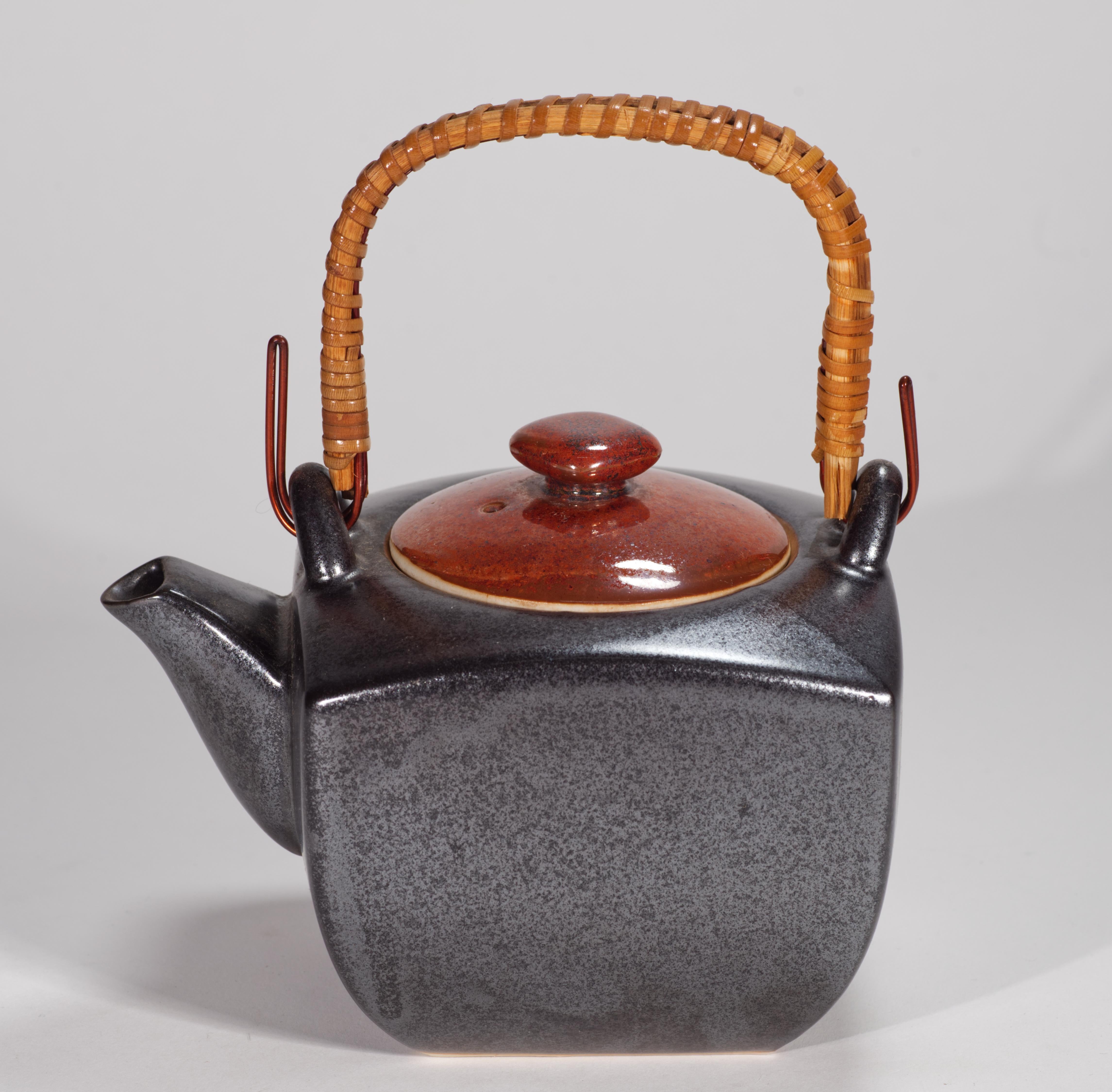  La tetera japonesa vintage está decorada con esmalte semimate de color marrón oscuro en el cuerpo y esmalte naranja quemado de alto brillo en la tapa; la paleta terrosa se complementa con el color madera natural del asa geométrica.

La tetera tiene