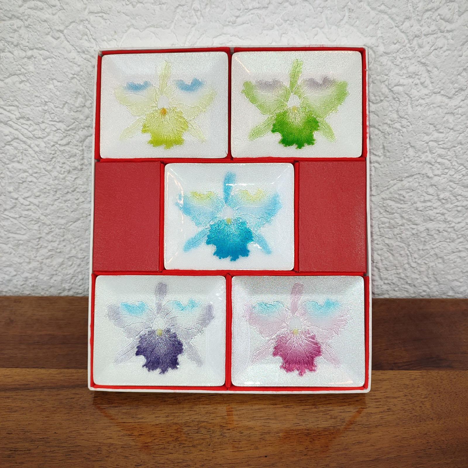Vintage Japanese Cloisonné Set von 5 Stück Sushi-Teller mit Orchidee Design, jedes in einer anderen Farbe. Im Originalkarton. Ausgezeichneter Zustand.
Abmessungen: 12x10 cm pro Stück, Schachtel 32x26x2 cm.