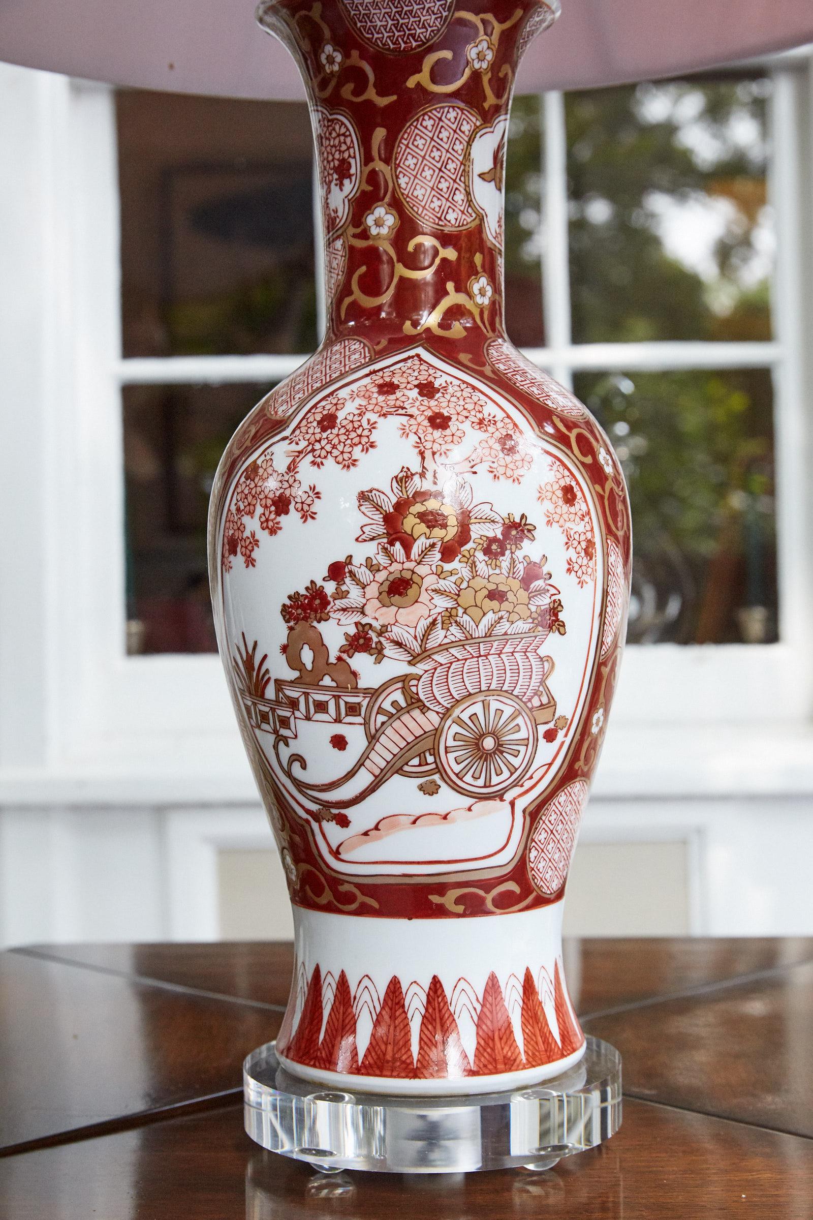 20th century vintage Japanese export Imari vase hand painted in hues of red and white with highlighted accents of blush and gold. The vase has been converted into a lamp and has updated wiring, a new Lucite base and finial, and a complimentary red
