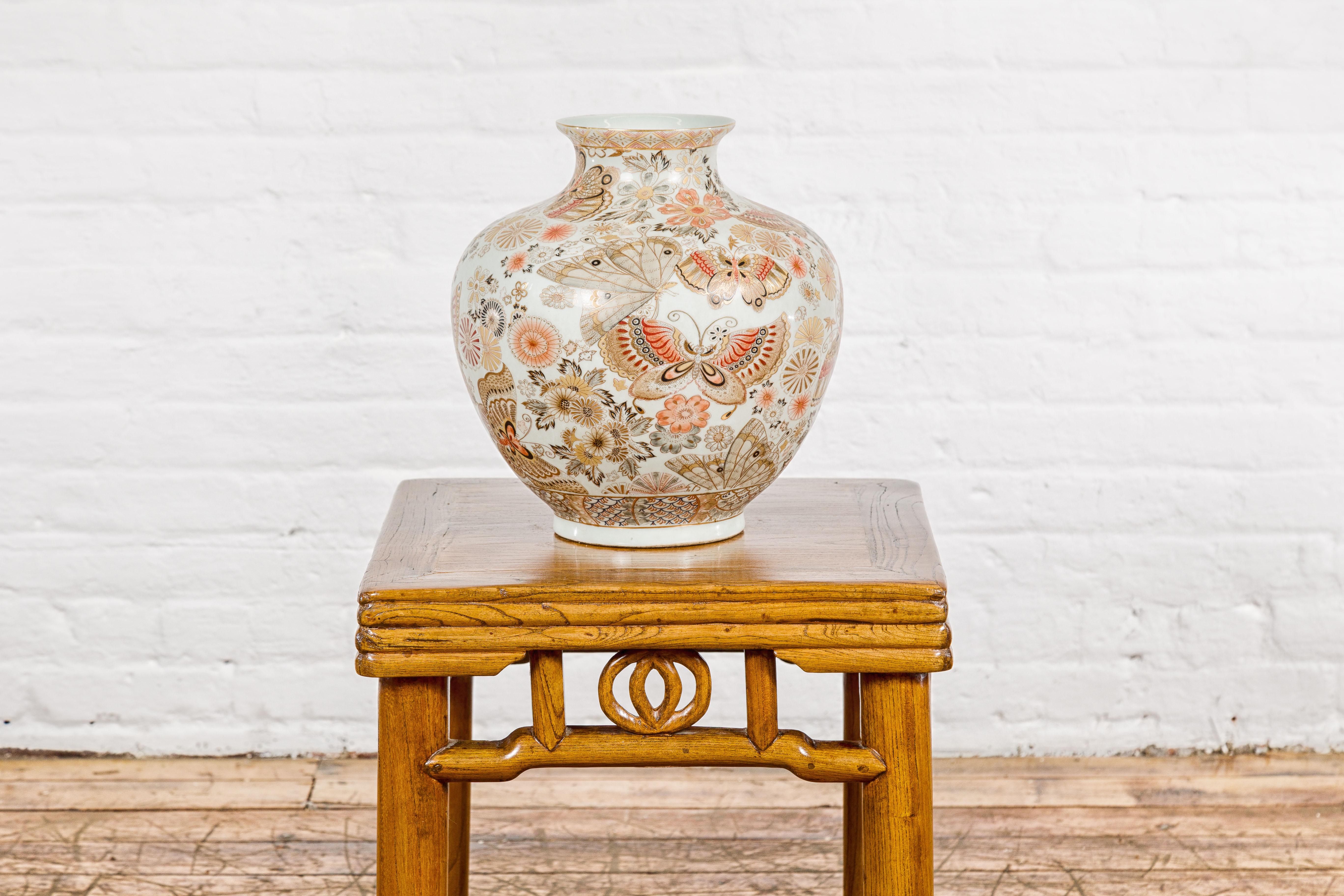A Chinese vintage Japanese Kutani style vase from the mid-20th century, with floral and butterfly decor. This Kutani-style vase, originating from mid-20th century China and inspired by Japanese artistry, is a celebration of beauty and intricacy.