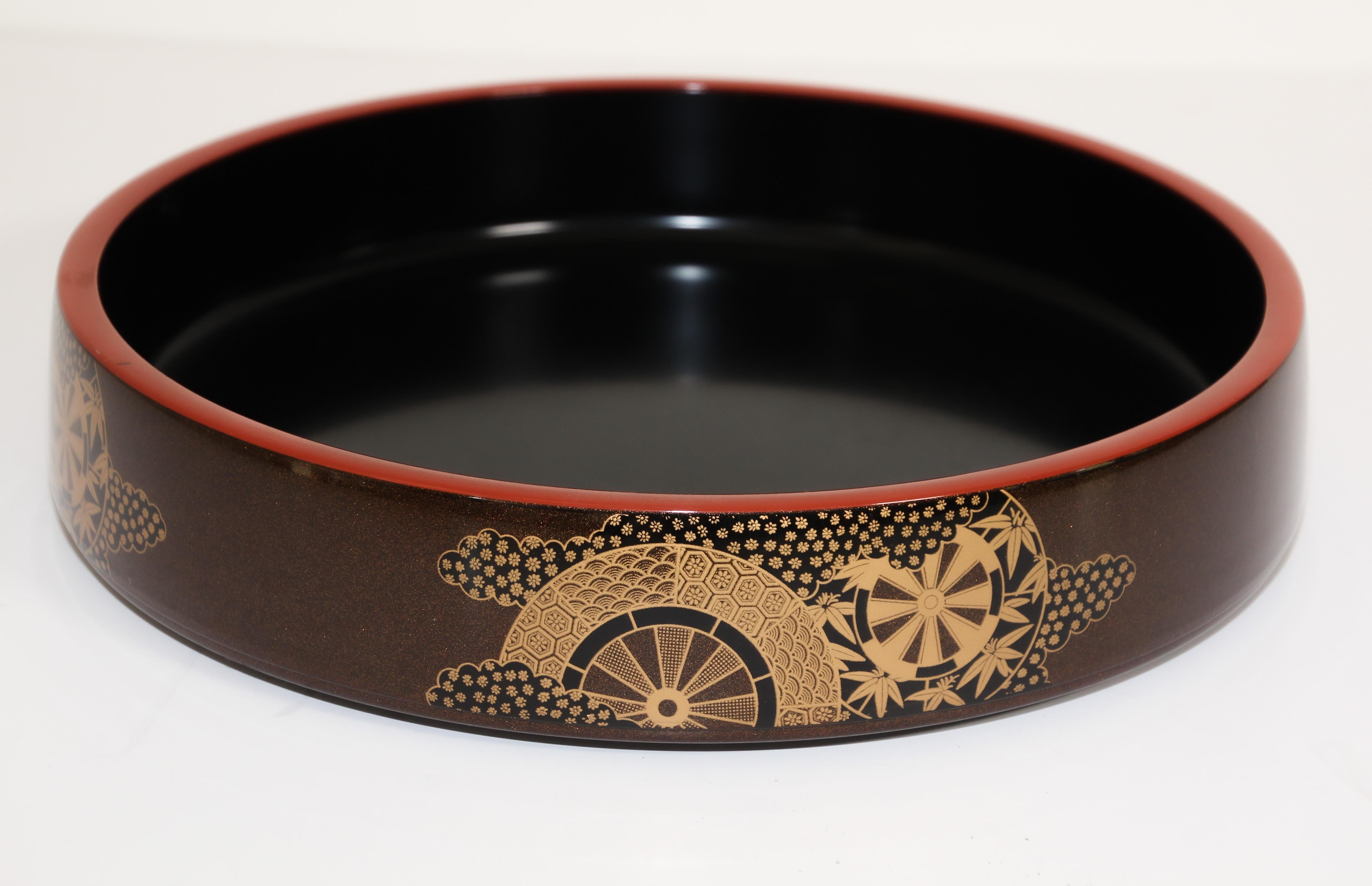Vintage Japanese lacquer ware circular tray.
Large round serving tray lacquered Japanese tray.
Black and red lacquered serving tray with a delicate gold leaf design painted around the outside tray rim with bamboo and fan design in gold accents