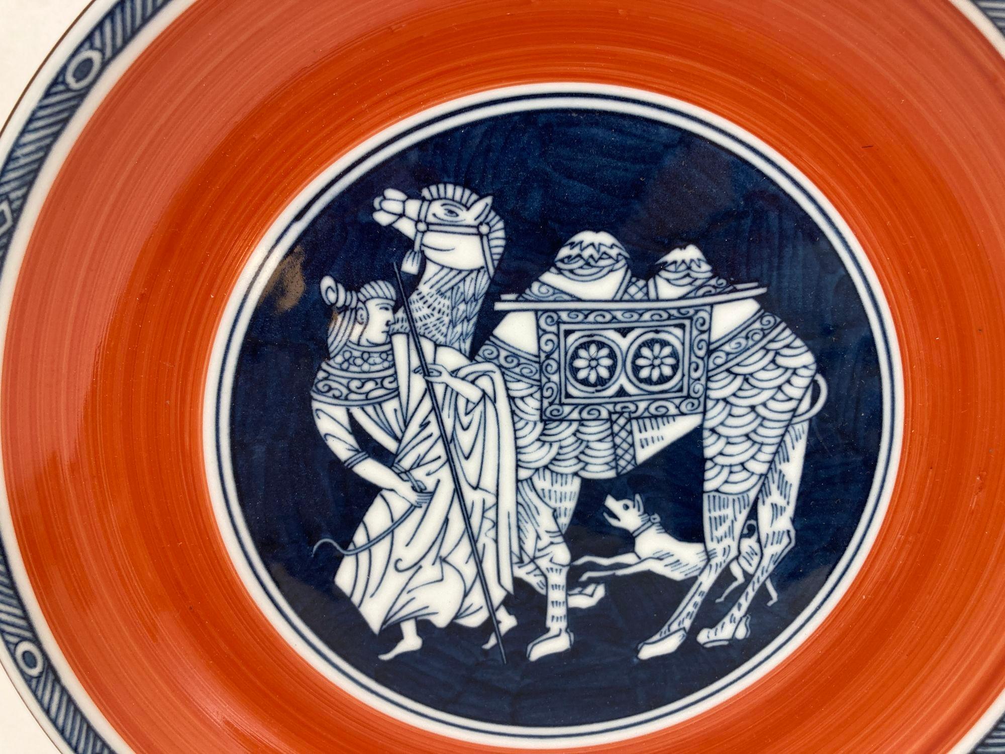 Grande porcelaine japonaise vintage peinte à la main avec des motifs d'orange et de kaki rouge et bleu.
Grand bol en céramique orange avec une scène d'un homme japonais portant un kimono traditionnel de samouraï et marchant avec un chameau et un