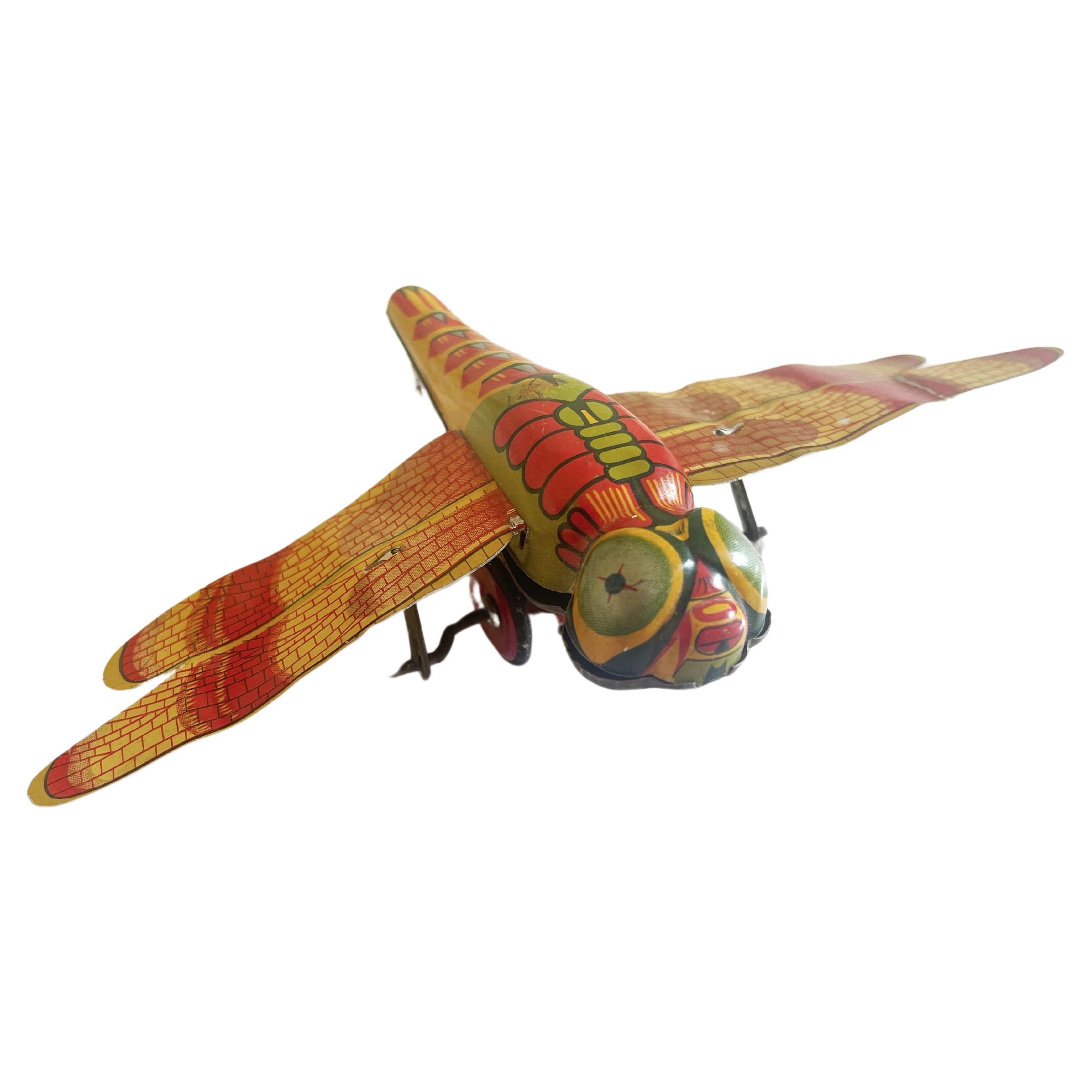 Japanese tin mechanical tin toy from the 1940s to 1950's in the shape of a dragonfly, which features flapping wings, once the 'beast' ist put in motion via it's wheels.
Beautiful litho printed in juicy colours of orange & red.
There is a lighter and