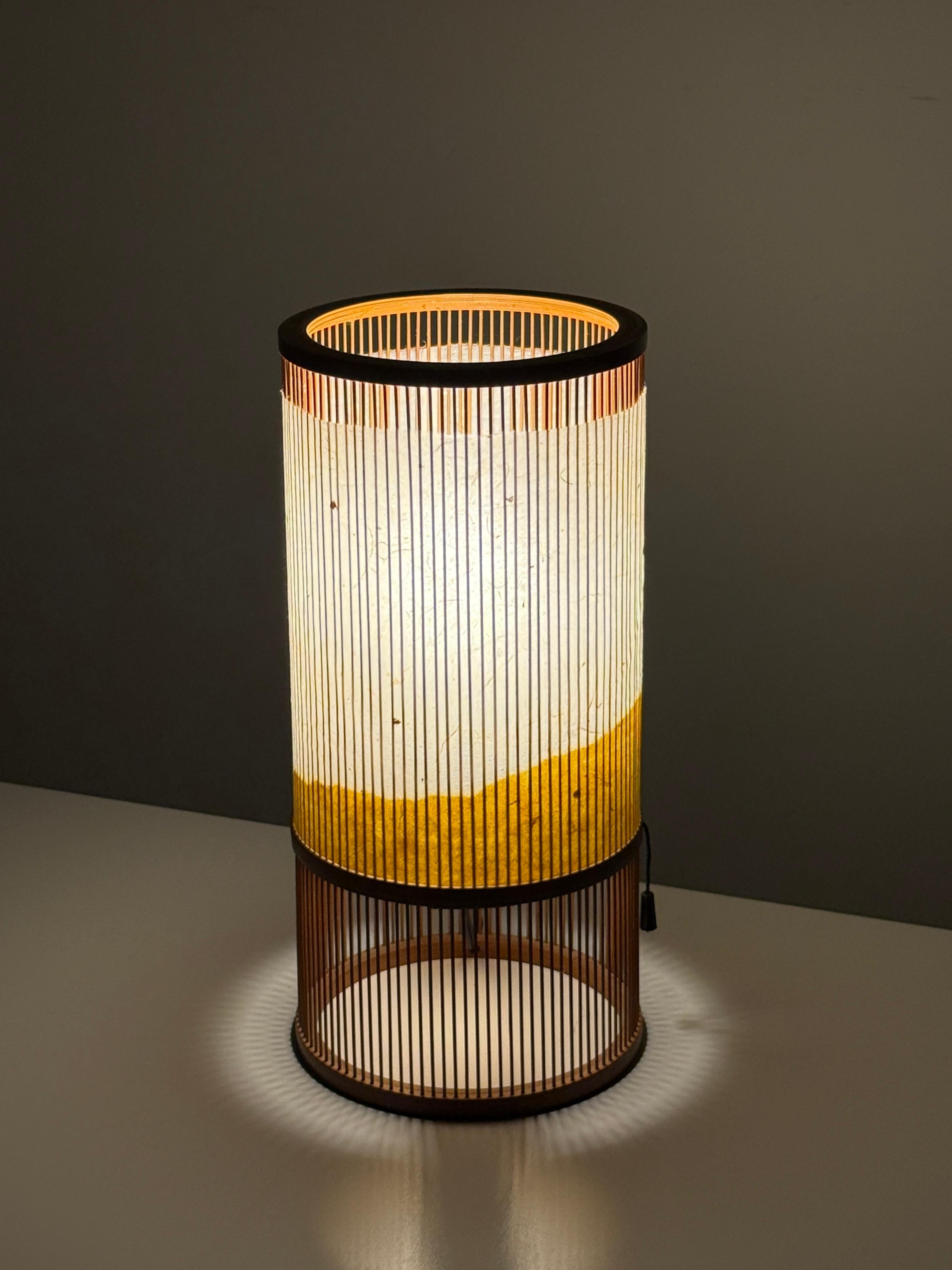 Vintage Miyabi Andon table lamp 
Japan circa 1980s

Cylindrical lantern constructed of bamboo and hand dyed washi paper in natural and yellow tones
Two internal sockets for variable ambient lighting

7 inch diameter
14.5 inch height