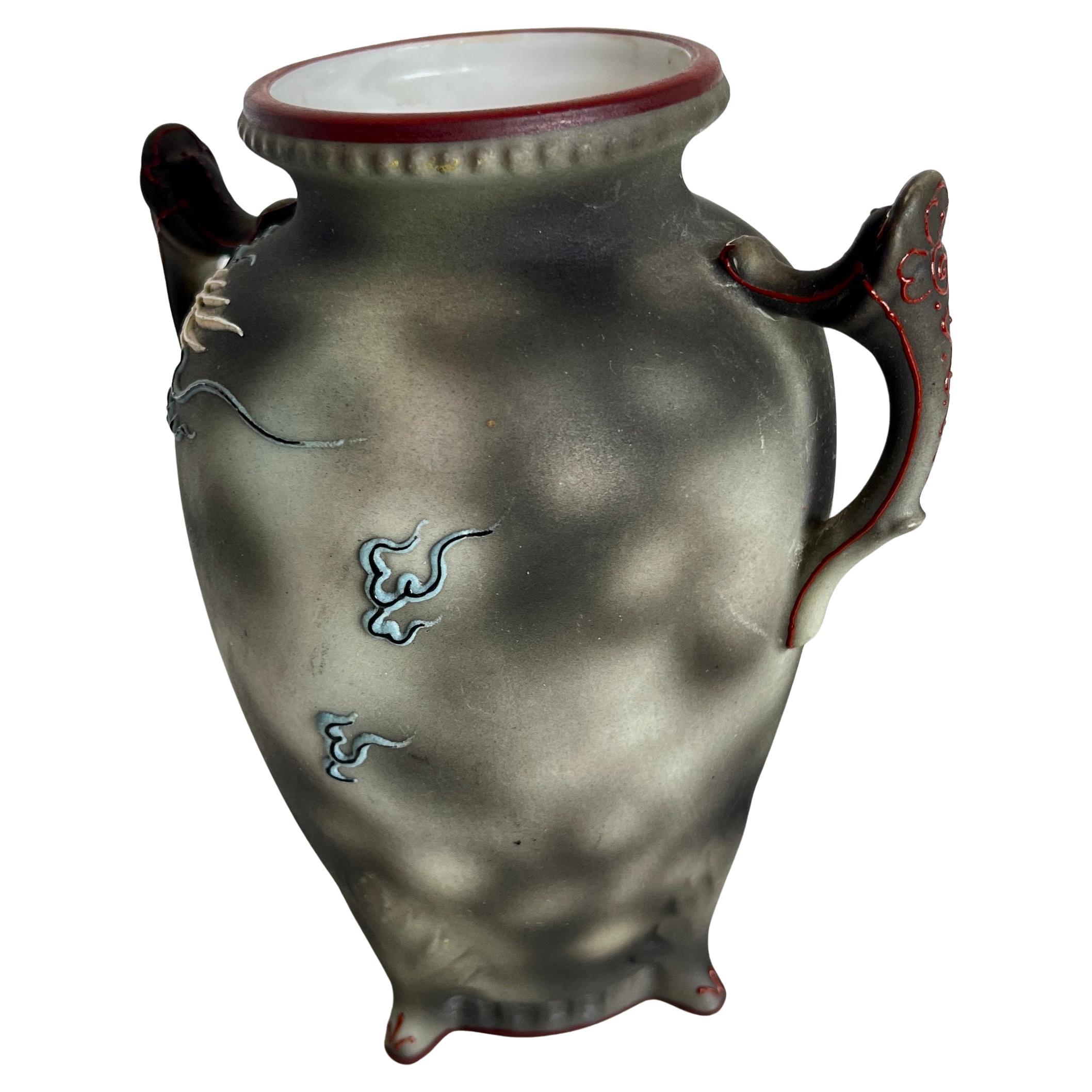 Japanese Noritake petite art vase. This elegant vase is moriage raised relief Dragonware; a dragon encircling the vase on a gray and black background. The intricate painting has splashes of blue, ivory and blush to enhance the body with bold