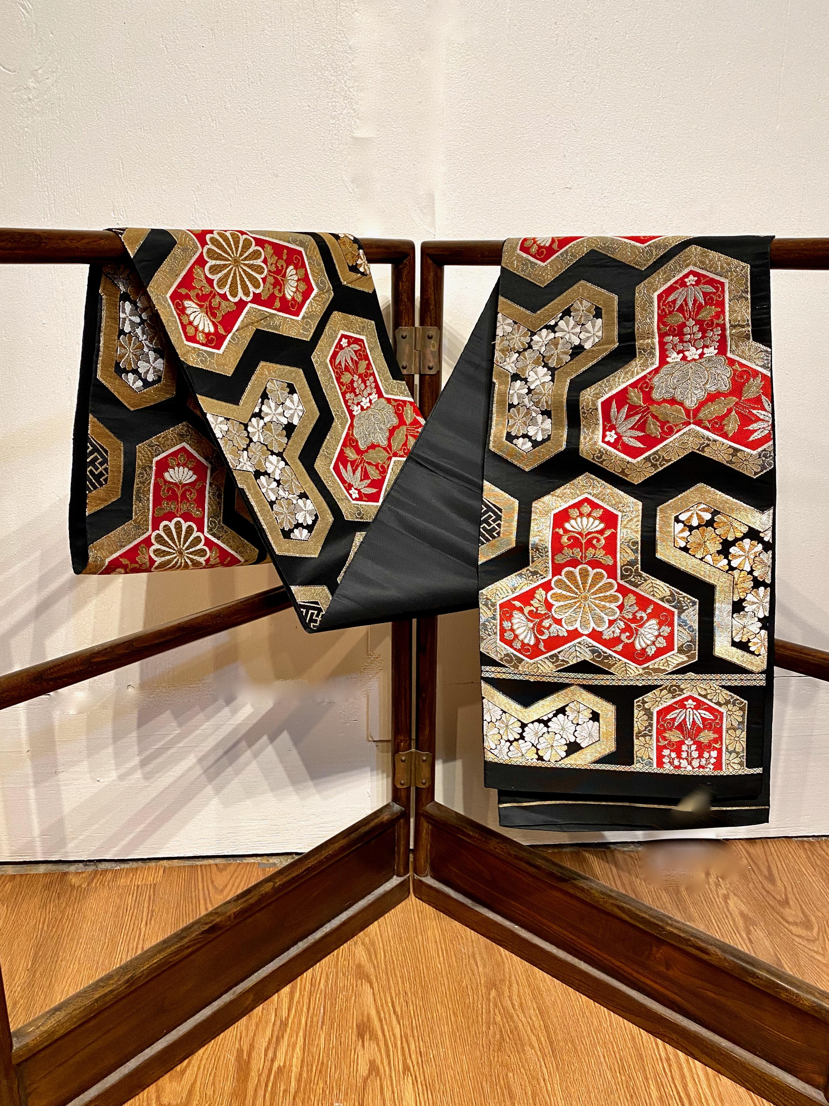 This is a stunning black silk obi that is decorated with red and gold reserves of brocade chrysanthemums. The design and quality of workmanship make this an exceptional obi that measures a very generous 160 inches in length by 13 wide. The brocade