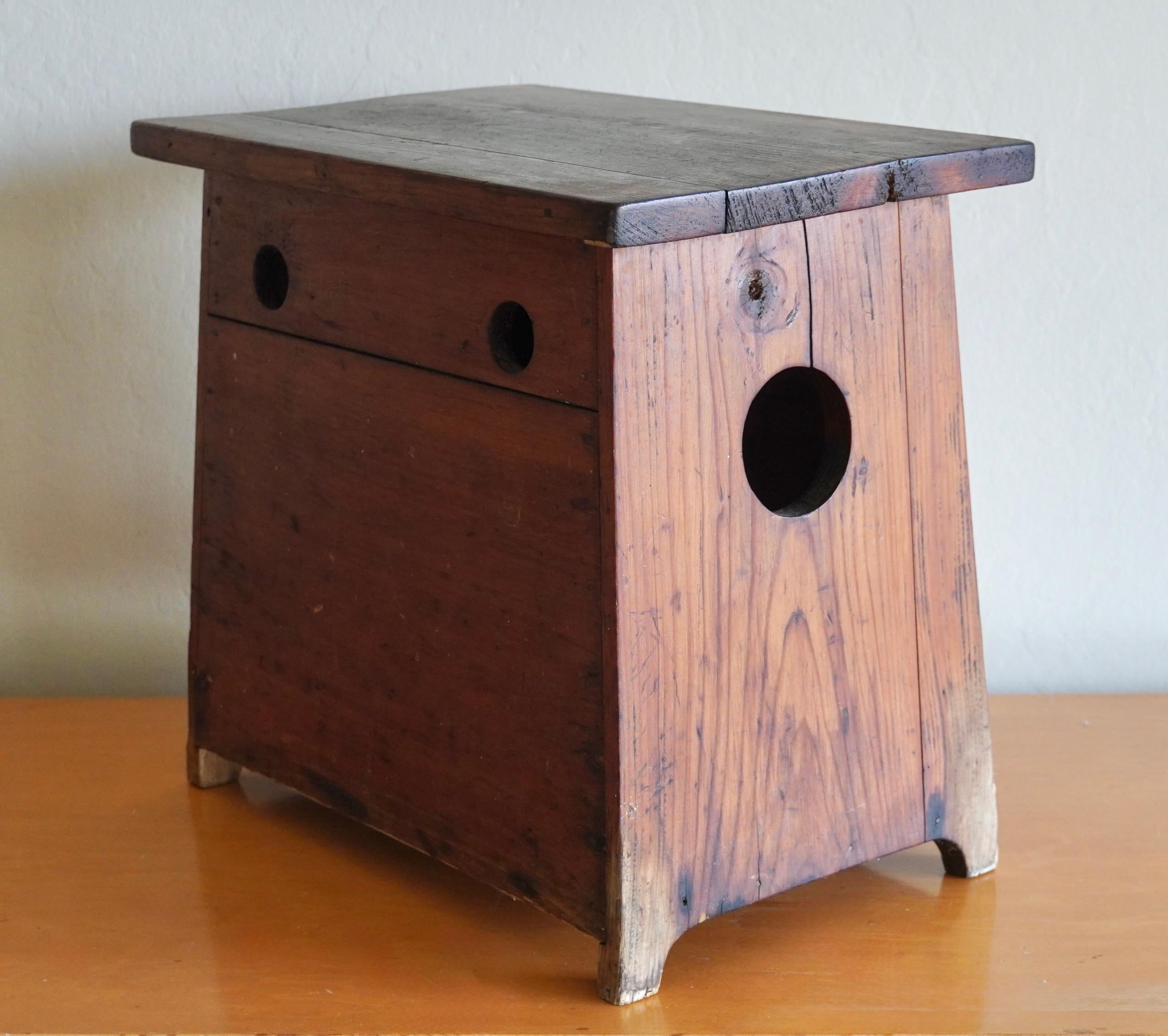 Lidded Japanese shop keepers stool from Japan with cut outs on both sides that are used as handles and for easy access to storage from within the stool. The wood and hardware has developed a rich patina from over the years from use and exposure to