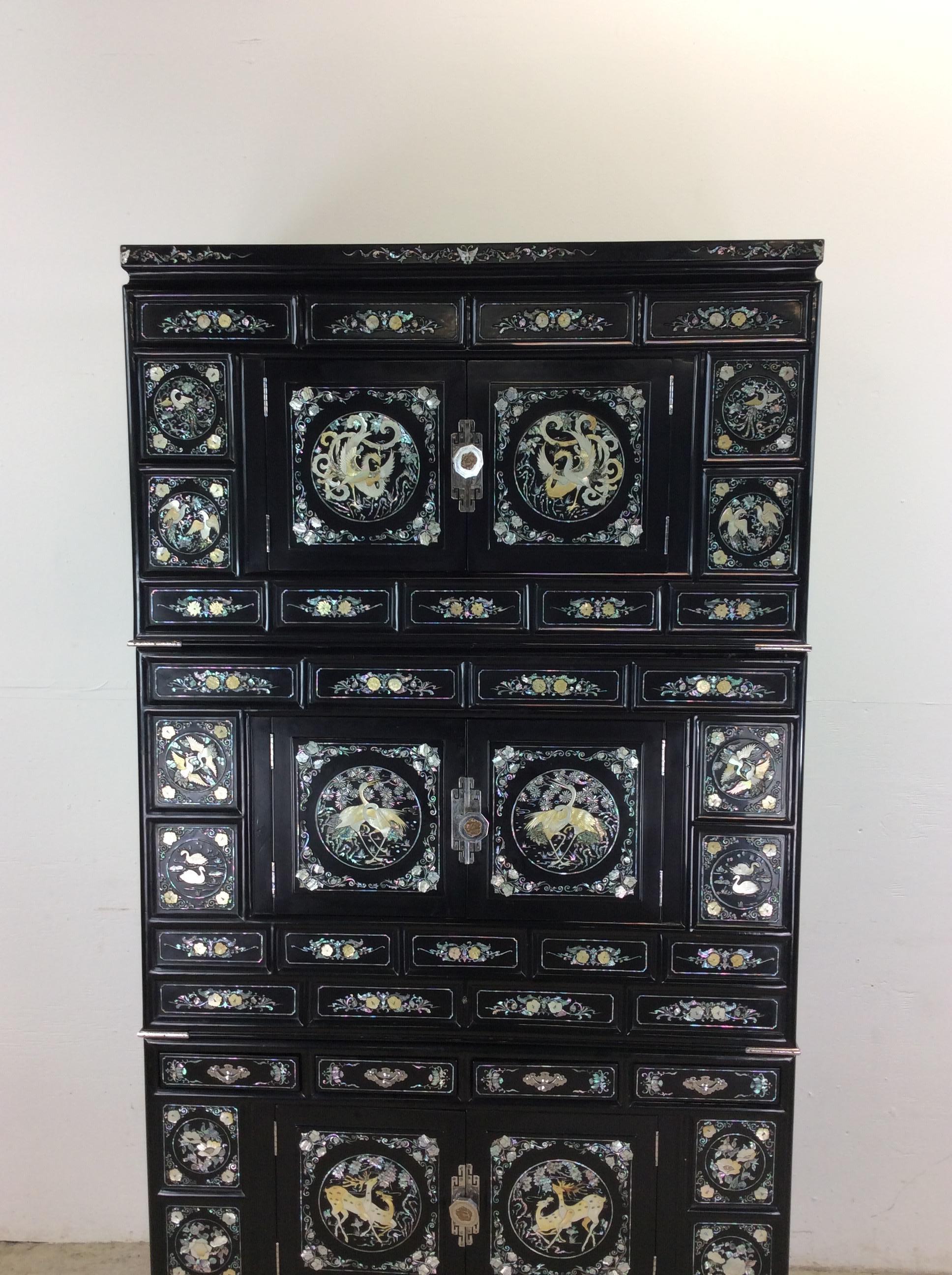 Cette armoire à tansu japonaise vintage est construite en bois (peut-être du balsa), peinte en noir avec des incrustations d'argent et de nacre. Elle est composée de trois boîtes modulaires avec des portes à charnières et des portes intérieures