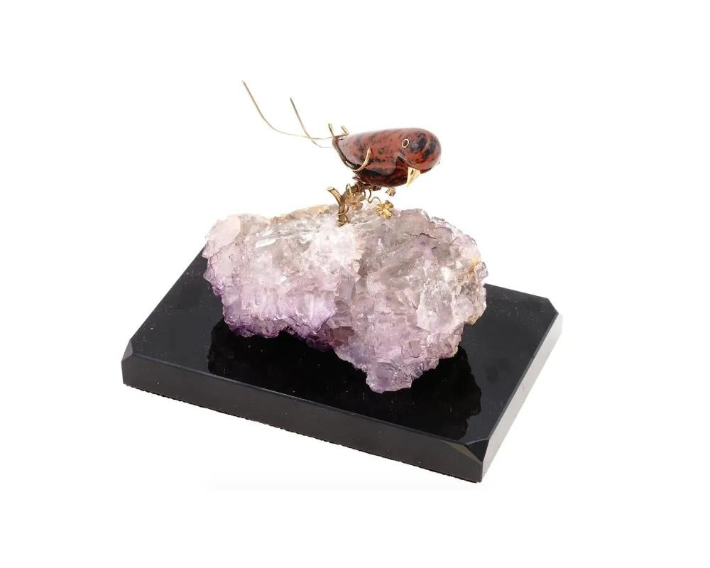 A vintage carved jasper bird with gold mounts showcasing the skill of lapidary artists who transform natural materials into breathtaking sculptures. The addition of gold mounts adds a touch of luxury and refinement to the piece. Perched on an