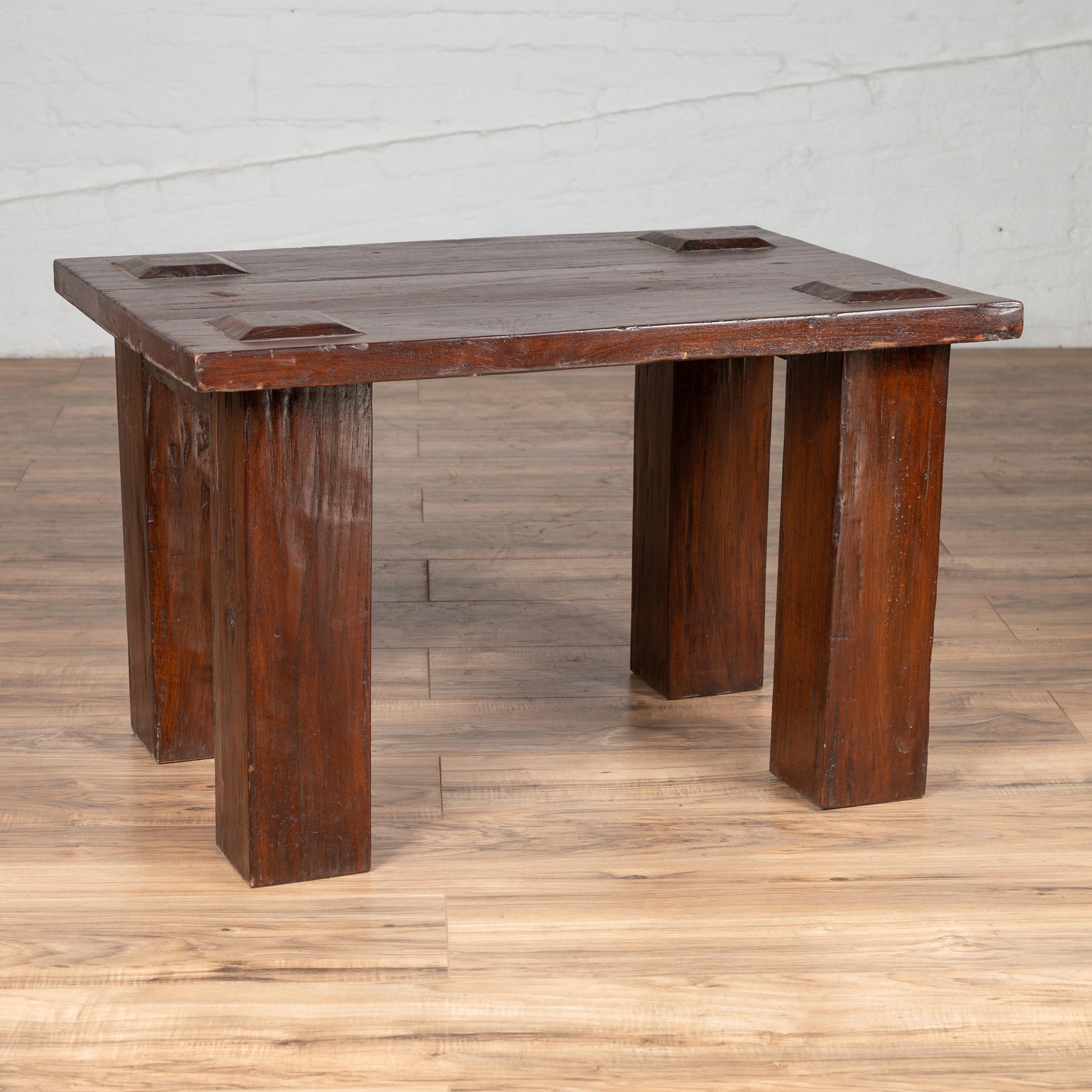 A vintage Javanese wooden bench from the mid-20th century, with raised motifs and straight legs. Born on the island of Java during the midcentury period, this wooden bench charms us with its rustic presence and simple lines. Featuring a rectangular