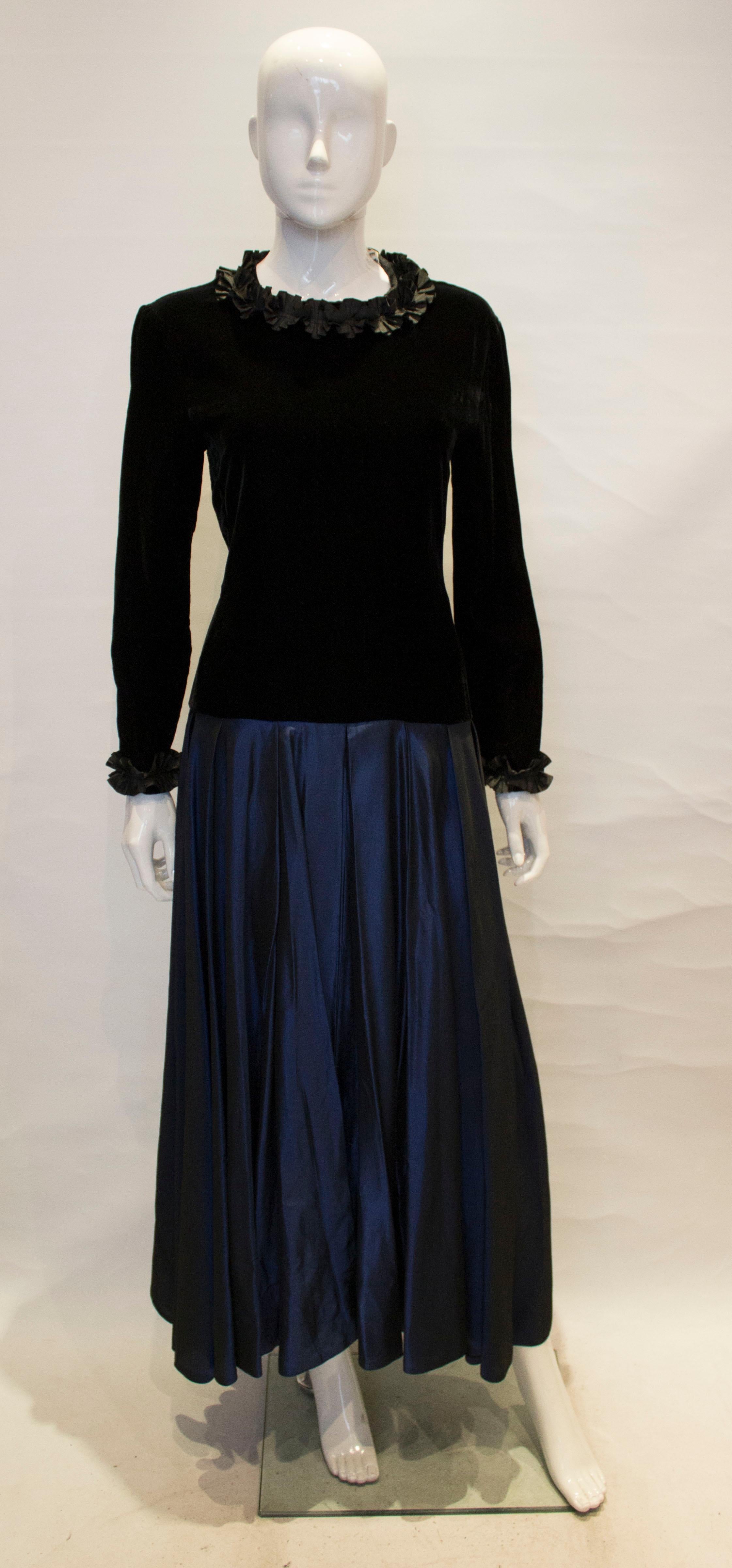 An elegant evening gown by Jeager.  The dress has a satin blue skirt  with a black velvet top , a central back zip and frills at the cuff and neckline.