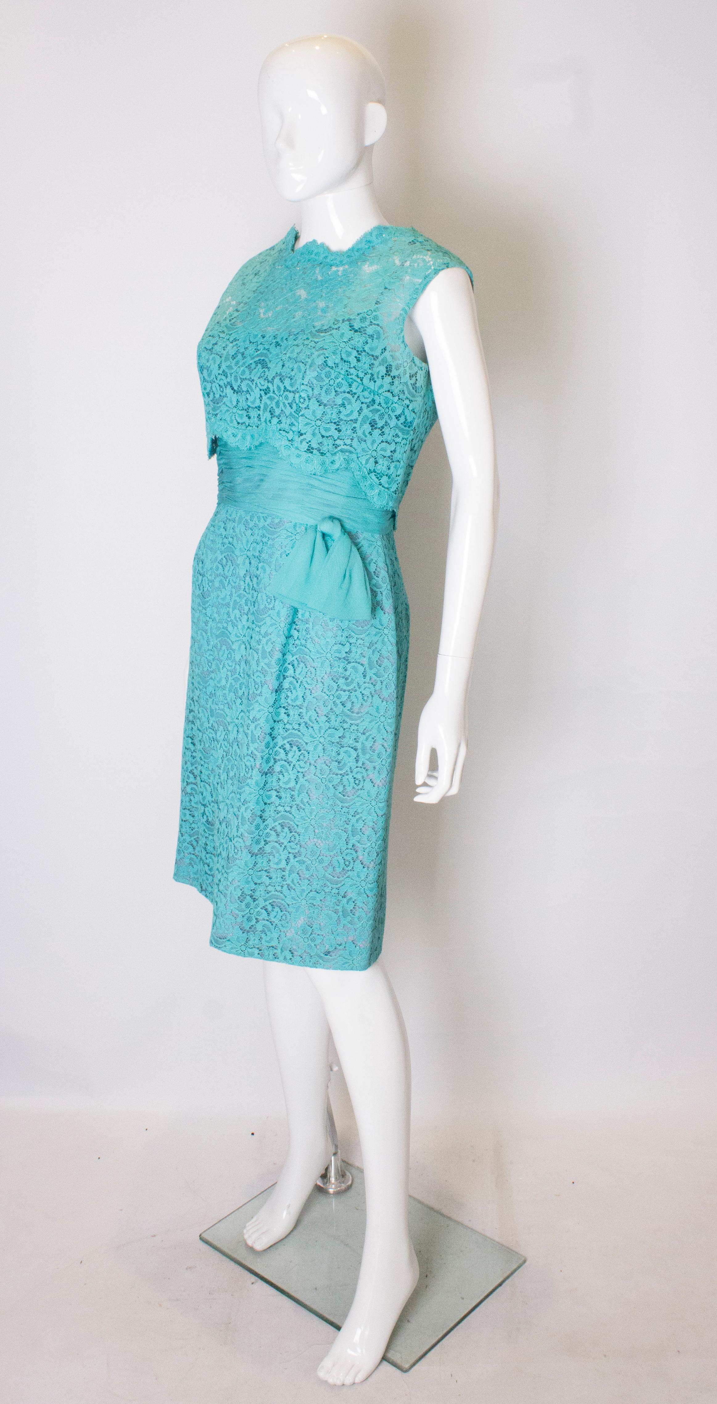A chic vintage cocktail dress in turquoise lace. The underdress has spagetti straps, a chiffon waist , lace skirt and a central back zip. The lace top has a scalloped back with popper fastenings. The dress has a 4 '' hem.
