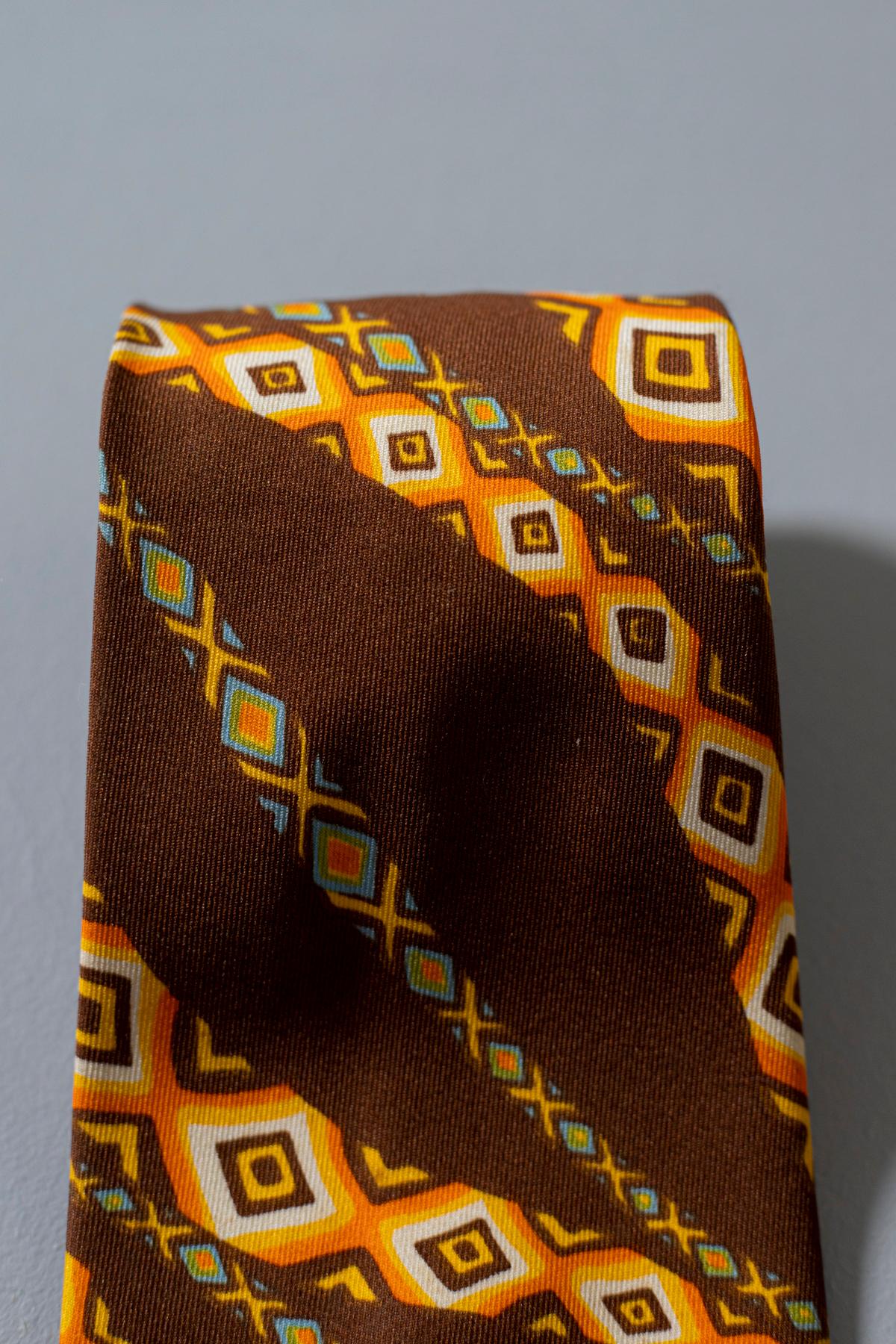 Particular and bizarre vintage tie made by the French designer Jean Claude, it is made of 100% silk. The predominant color is brown and is decorated with wavy yellow stripes with small rhombuses inside. It is a particular accessory ideal for an