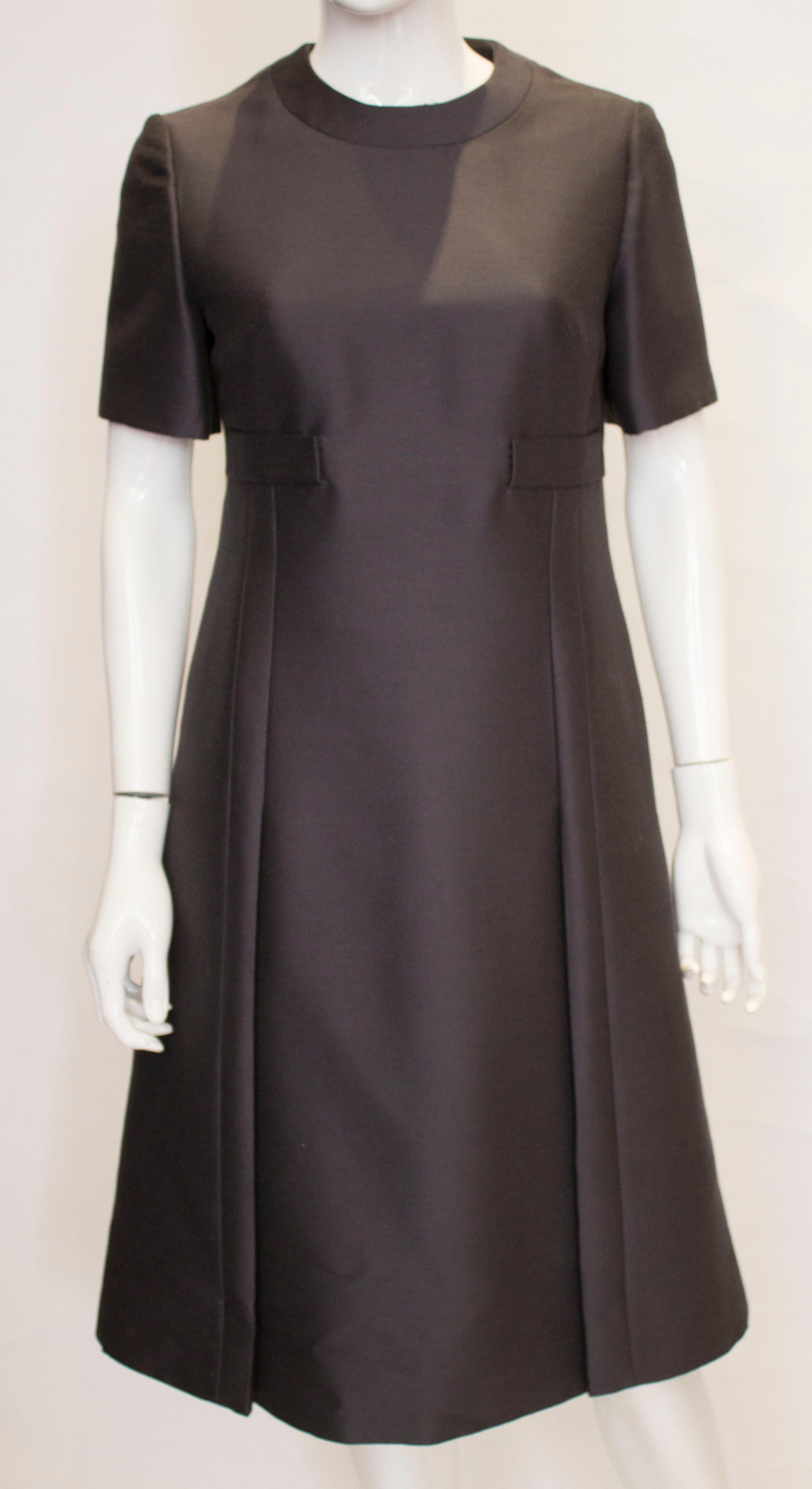 An elegant power dressing outfit by Jean Patou. In a steel grey colour , the dress has a round collar, flare detail at the front , short sleeves and a central back zip.
The coat has elbow length sleeves , a drop collar detail , six button front