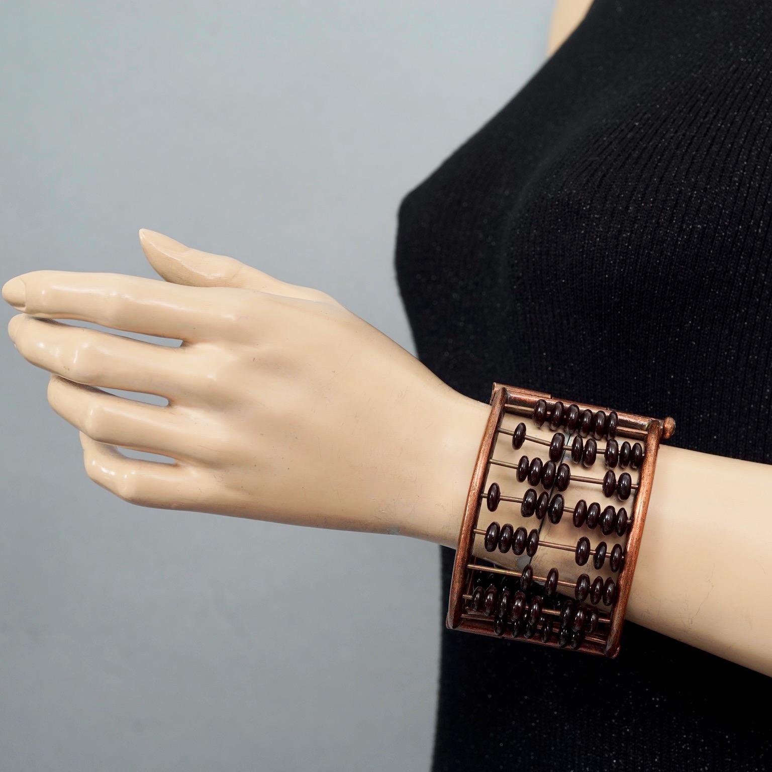 Vintage JEAN PAUL GAULTIER Abacus Cuff Bracelet

Measurements:
Height: 2.16 inches (5.5 cm)
Wearable Length: 7.28 inches (18.5 cm)

Features:
- 100% Authentic JEAN PAUL GAULTIER.
- Abacus style cuff bracelet with brown beads embellishment.
- Bronze