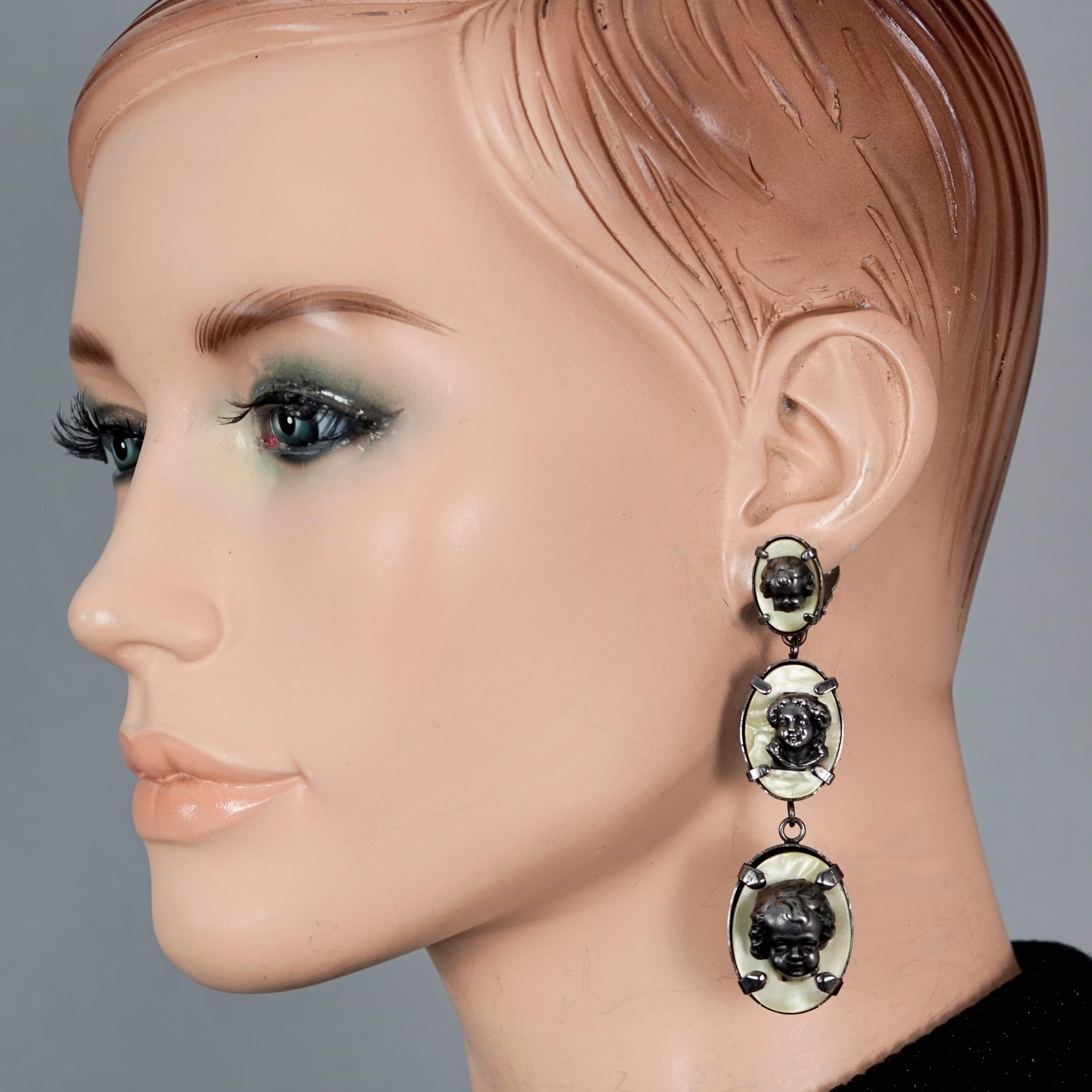 Vintage JEAN PAUL GAULTIER Cherub Nacre Dangling Earrings

Measurements:
Height: 3.34 inches (8.5 cm)
Width: 0.87 inch (2.2 cm)
Weight per Earring: 19 grams

Features:
- 100% Authentic JEAN PAUL GAULTIER.
- Raised metal cherub head on iridescent