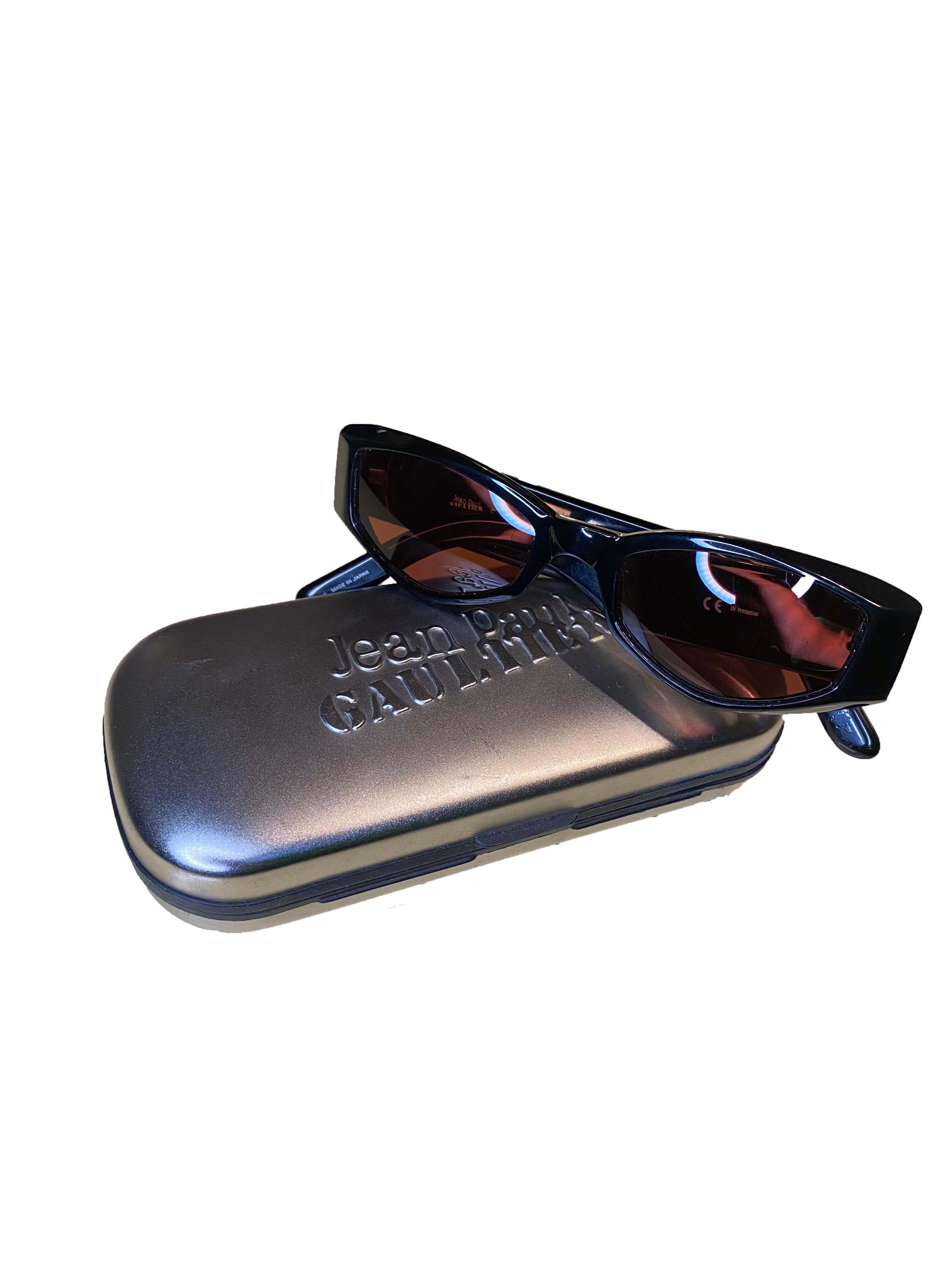 Vintage-Sonnenbrille von Jean Paul Gaultier. Solider schwarzer Rahmen aus glattem Acetat. Bronzefarbener Metalldrache, der in beide Beine eingelassen ist. Dunkle Gläser mit leicht violetter Tönung. Das Markenzeichen von Jean Paul Gaultier befindet