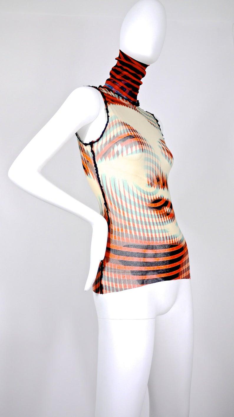 Vintage JEAN PAUL GAULTIER Face Optic Illusion Print Turtle Neck Blouse

Measurements taken laid flat, please double bust and waist:
Turtle Neck: 6 4/8 inches
Shoulder: 12 4/8 inches
Bust: 14 4/8 inches (without stretching)
Waist: 12 inches (without