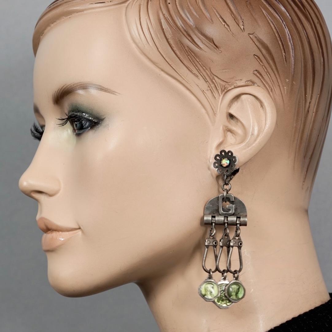 Vintage JEAN PAUL GAULTIER Flower Scapular Religious Charm Dangling Earrings

Measurements:
Height: 3.42 inches (8.7 cm)
Width: 1.38 inches (3.5 cm)
Weight per Earring: 14 grams

Features:
- 100% Authentic JEAN PAUL GAULTIER.
- Flower rhinestone