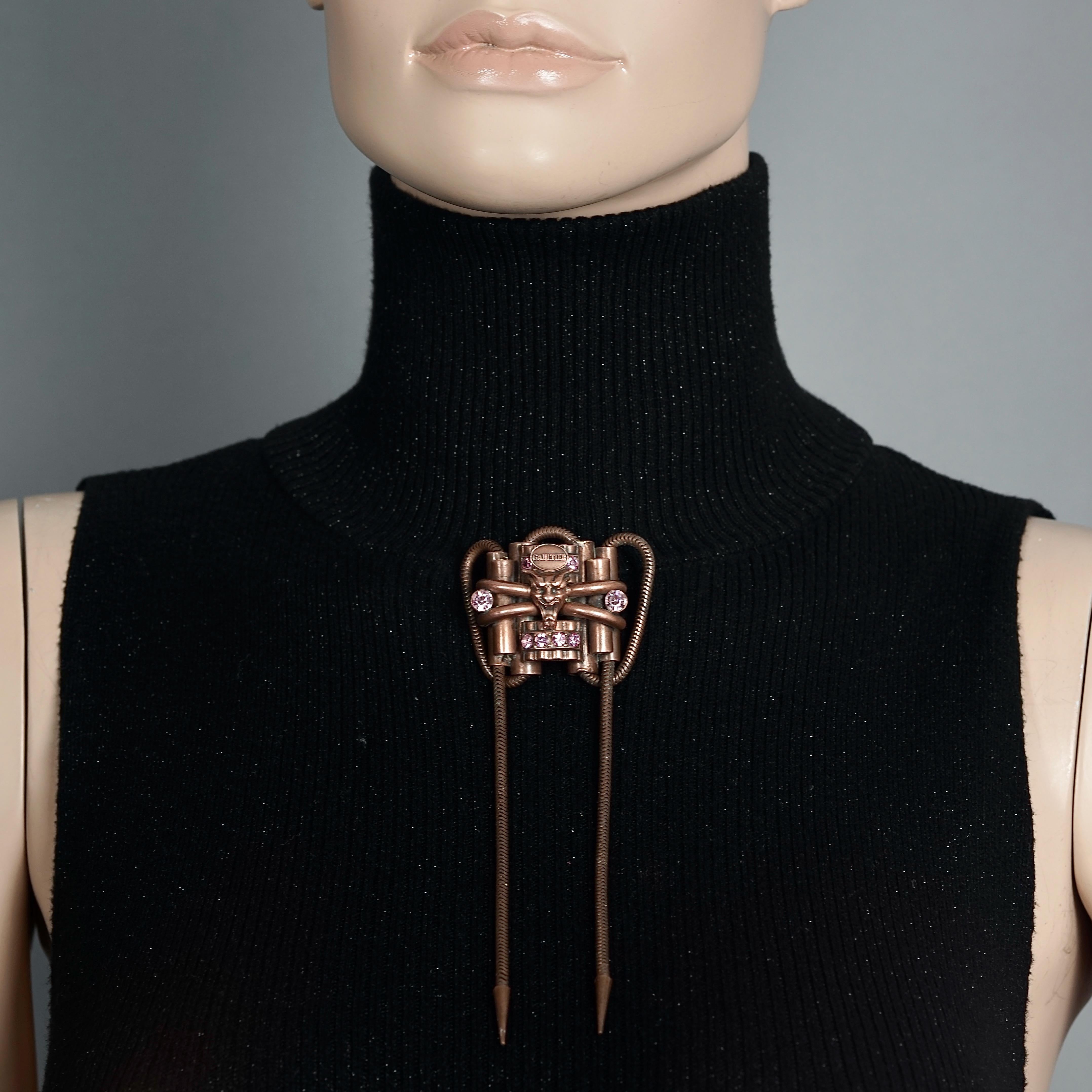 Vintage JEAN PAUL GAULTIER Gargoyle Tubular Dangling Chain Gothic Brooch

Measurements:
Height: 5.90 inches (15 cm)
Width: 1.57 inches (4 cm)

Features:
- 100% Authentic JEAN PAUL GAULTIER.
- 3 dimensional gargoyle with pink rhinestones, dangling