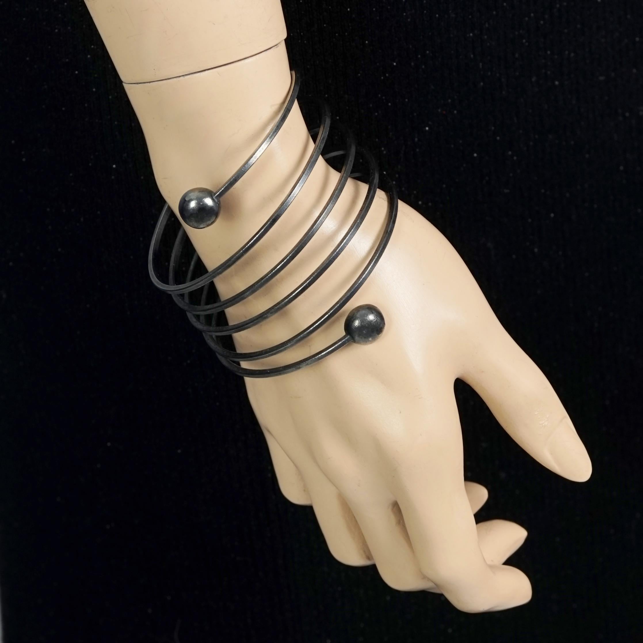 Vintage JEAN PAUL GAULTIER Gothic Coil Cuff Bracelet

Measurements:
Height: 2.75 inches (7 cm)
Inner circumference: 7.87 inches (20 cm)

Features:
- 100% Authentic JEAN PAUL GAULTIER.
- Coil cuff bracelet with circular ends.
- Gunmetal tone