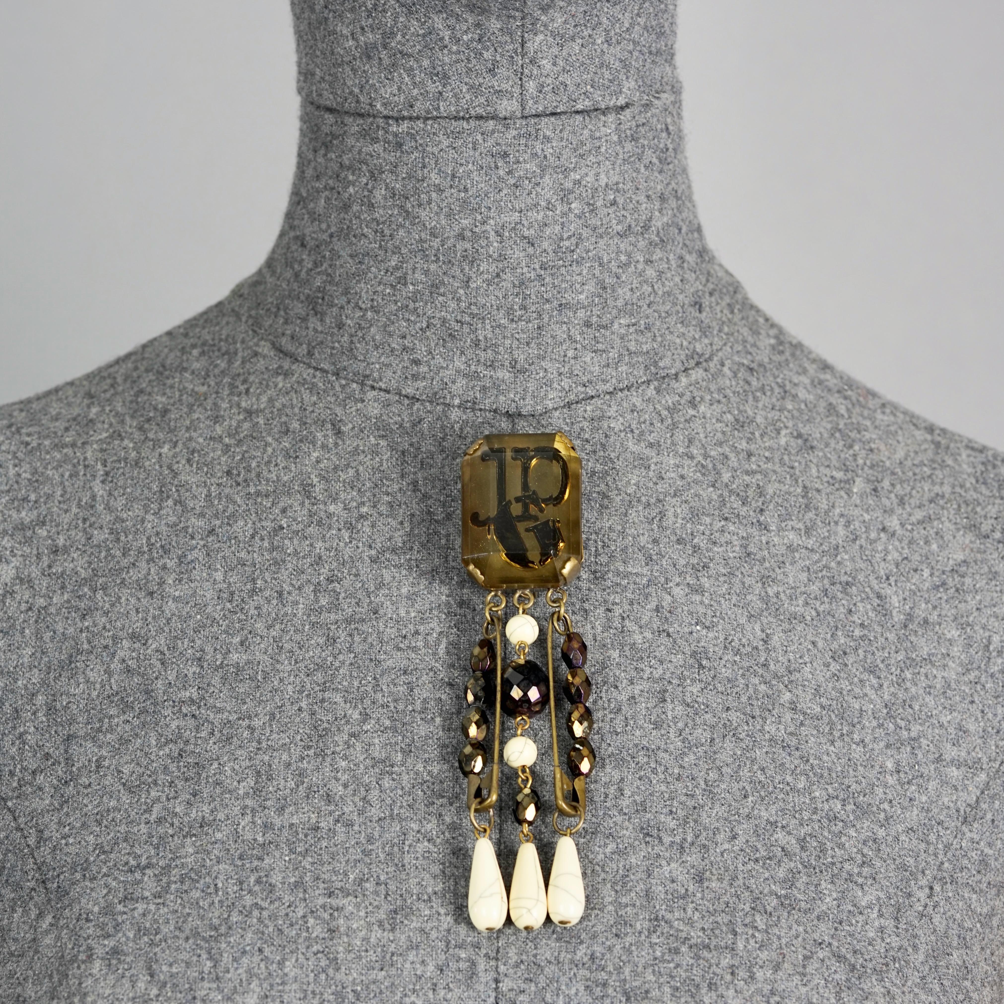 Vintage JEAN PAUL GAULTIER Logo Safety Pin Lucite Beaded Brooch

Measurements:
Height: 5.03 inches (12.8 cm)
Width: 1.14 inches (2.9 cm)

Features:
- 100% Authentic JEAN PAUL GAULTIER.
- Faceted lucite rectangular brooch with JGP logo and beaded