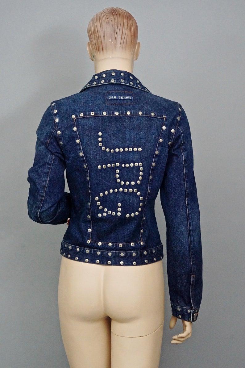 Vintage JEAN PAUL GAULTIER Logo Studded Denim Jacket

Measurements taken laid flat, please double bust and waist:
Shoulder: 15.74 inches (40 cm)
Sleeves: 24.80 inches (63 cm)
Bust: 19.09 inches (48.5 cm)
Waist: 15.74 inches (40 cm)
Length: 18 4/8