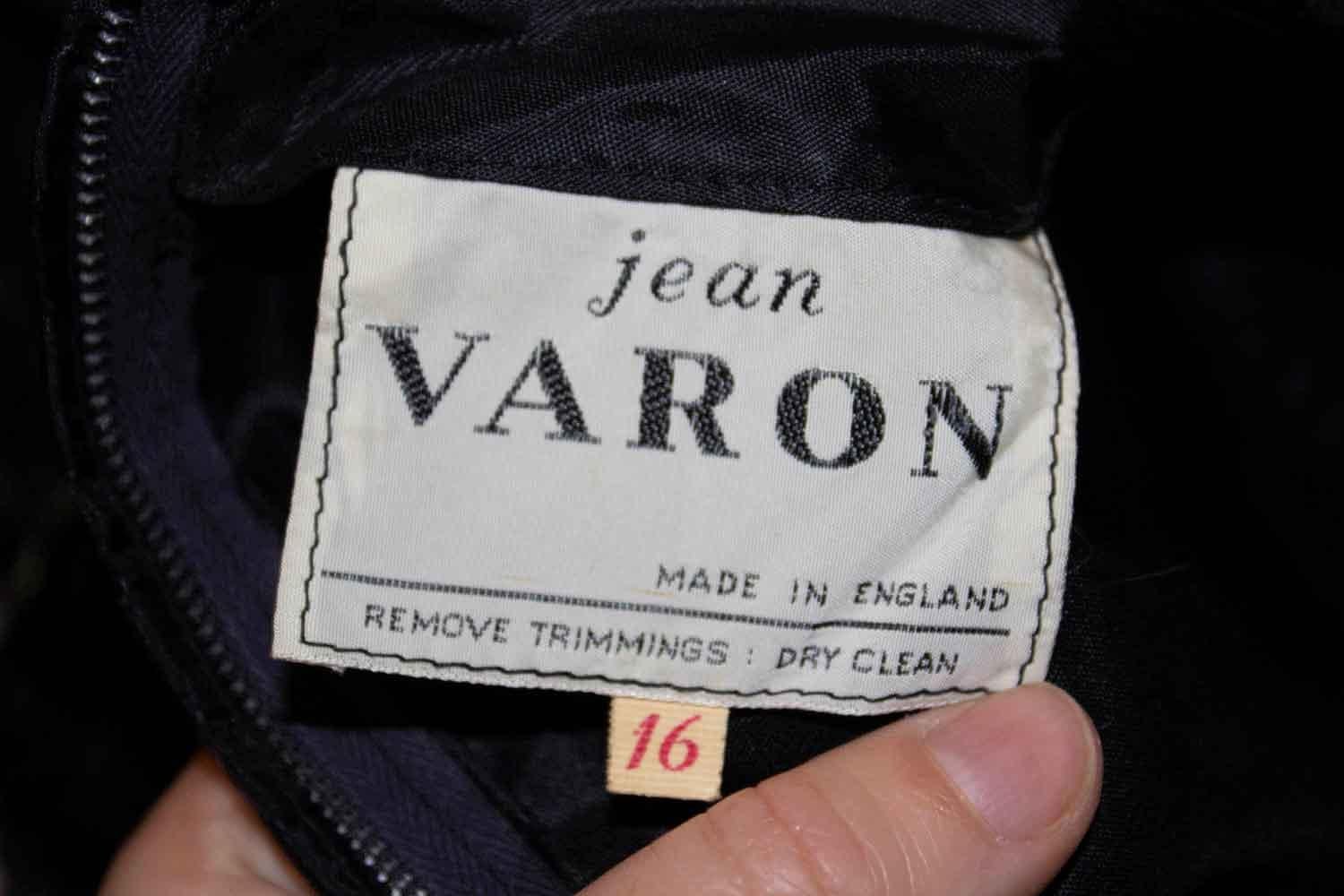 Une robe vintage de Jean Varon qui fait tourner les têtes et qui est facile à porter. La robe est en ruban noir et en dentelle, avec un col rond, des manches courtes et une jupe de type A line. Il possède une ouverture centrale zippée au dos et est