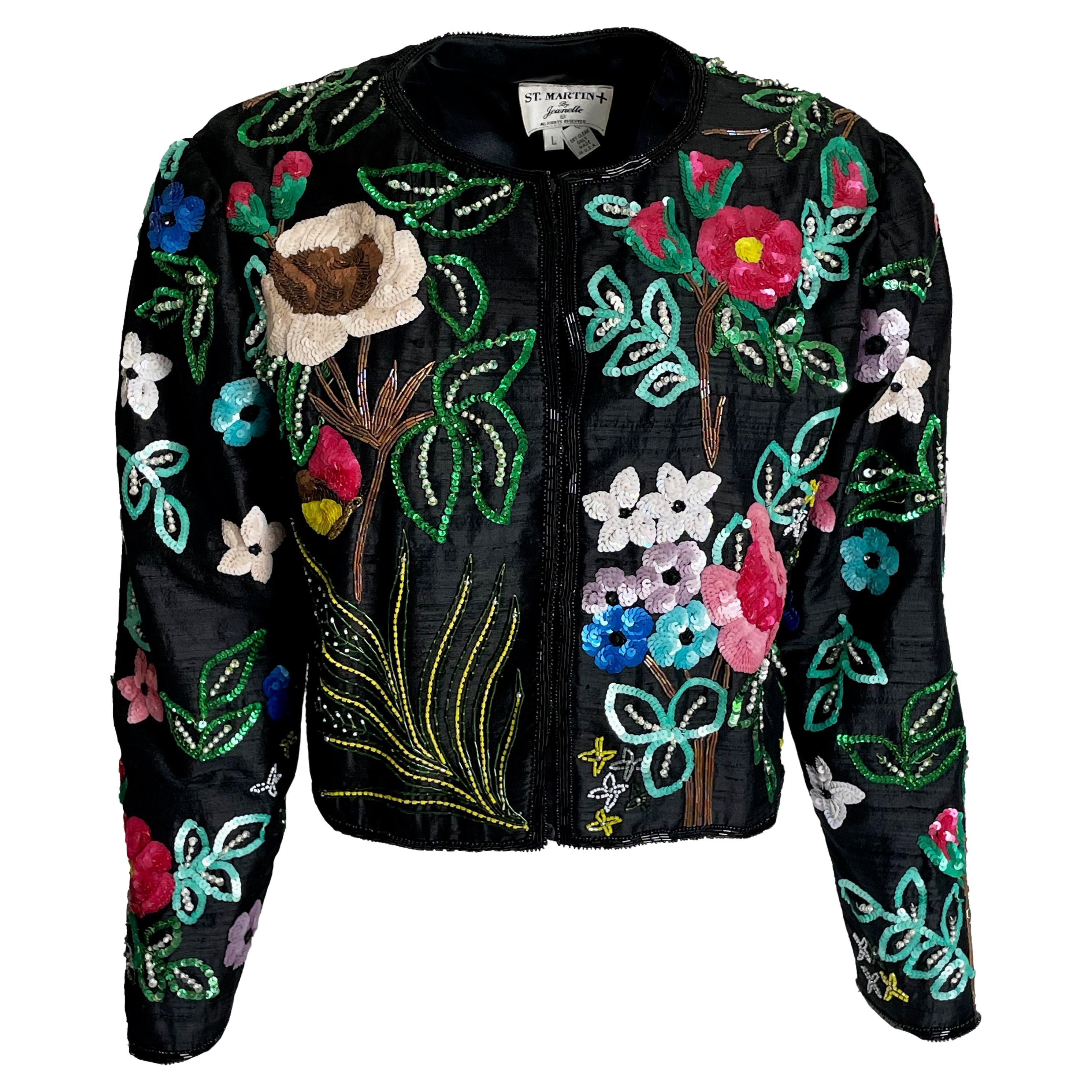 Dieses Bolero-Jackett von Jeanette Kastenberg für St. Martin aus den 1980er-Jahren ist ein schillerndes Statement aus schwarzer Seide, das mit lebhaften, handgekettelten Blumenmotiven verziert ist. Diese kühne, leuchtende und unverkennbar festliche