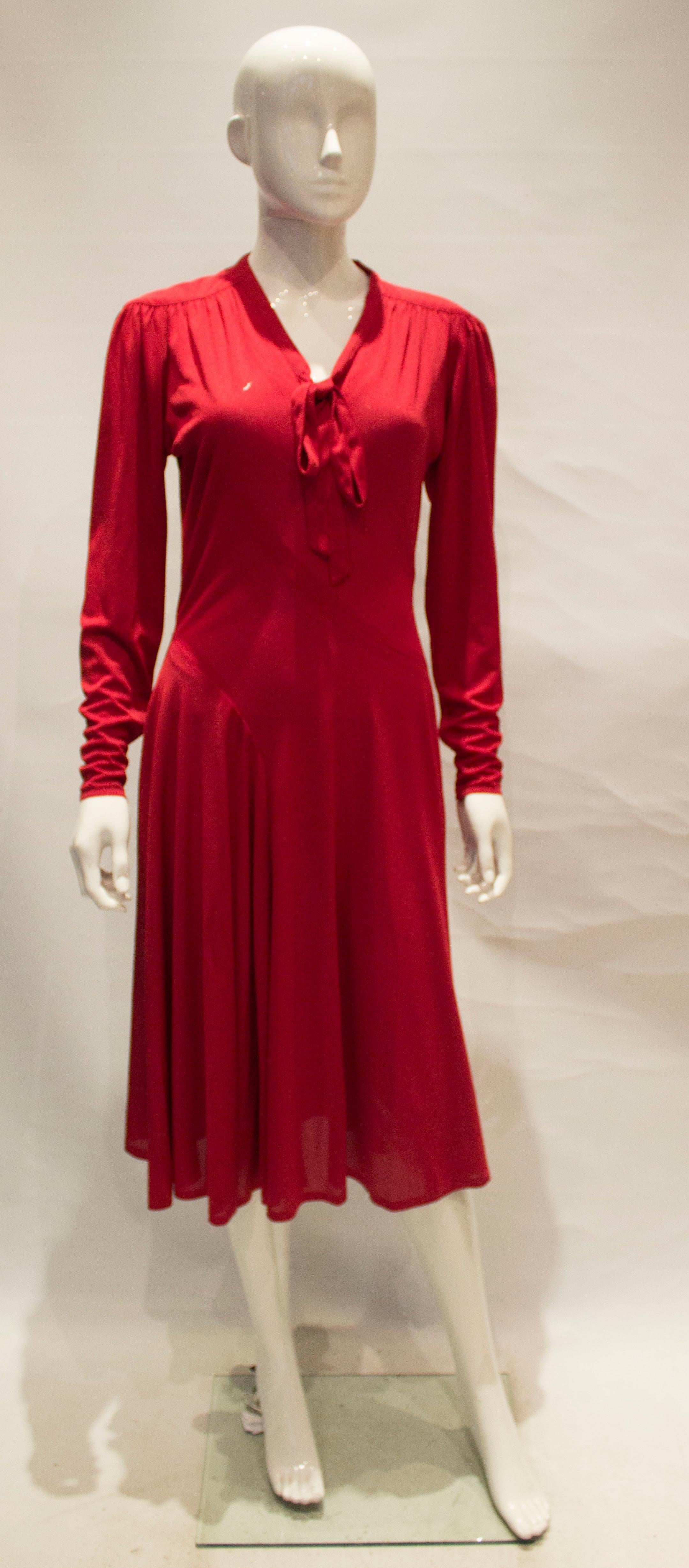 A chic and easy to wear dress from Jerseymasters. In a lovely shade of red  the dress has a v neckline with tie and a self fabric tie belt.