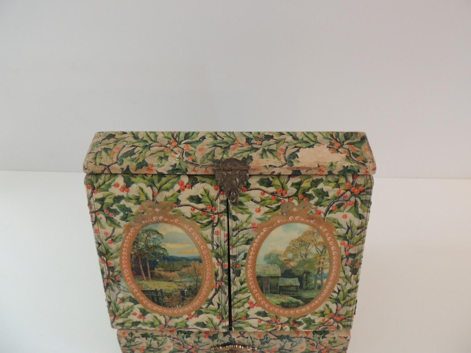 Vintage jewelry box cover in holly pattern paper and laminated doors.
Inside mirrors and lining. Red and white rope trim around the mirrors.
Drawer in the bottom and delicate brass hardware.
Is a beautiful display case.
(some parts have missing